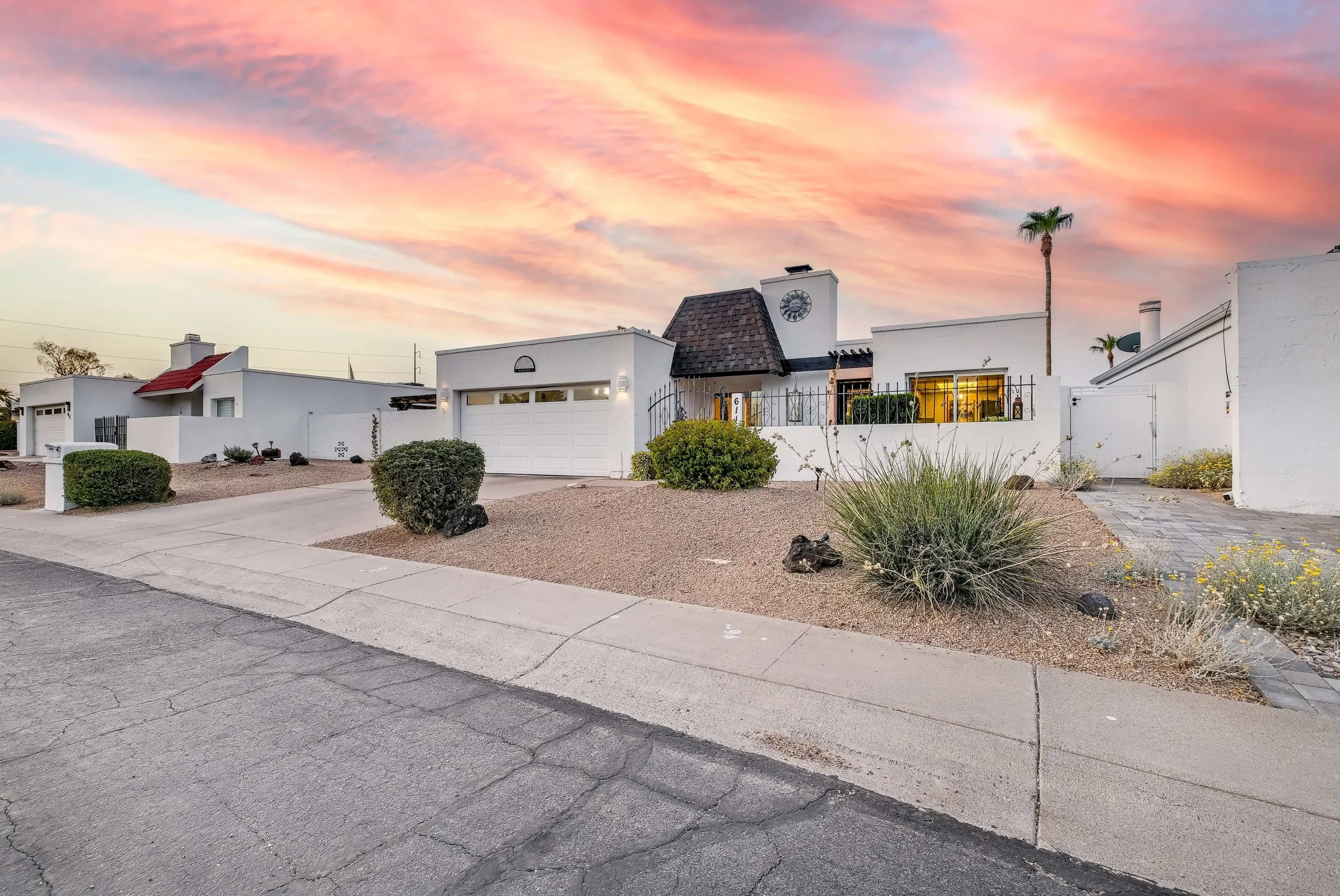 A stunning twilight exterior view of a single-family luxury home with a pristine white facade and desert landscaping on Tam O Shanter Drive in Phoenix, Arizona.