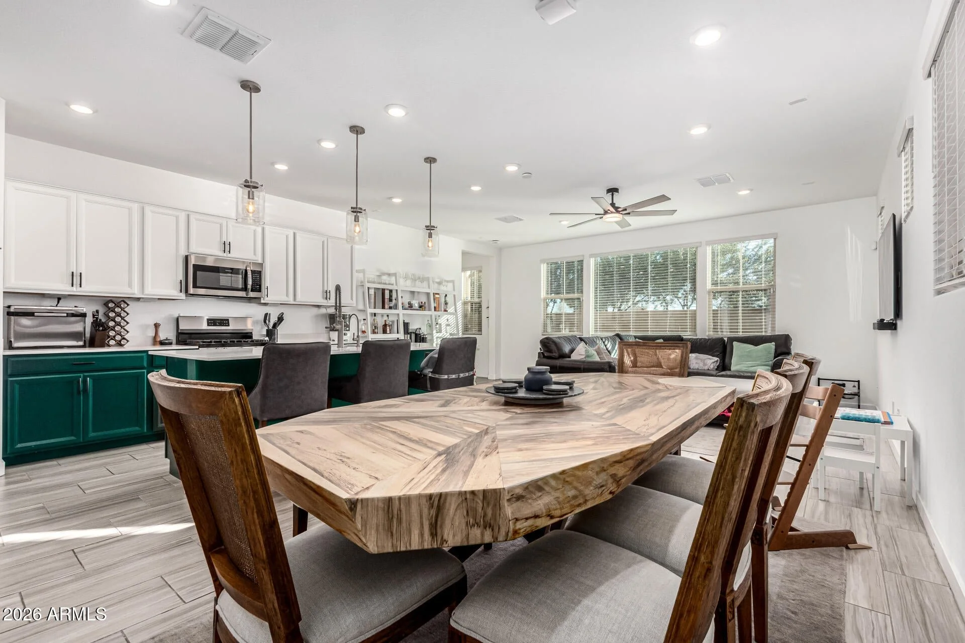 Open-concept kitchen and living room in a modern Chandler, Arizona home for sale featuring quartz countertops, large island, gas range, and contemporary finishes
