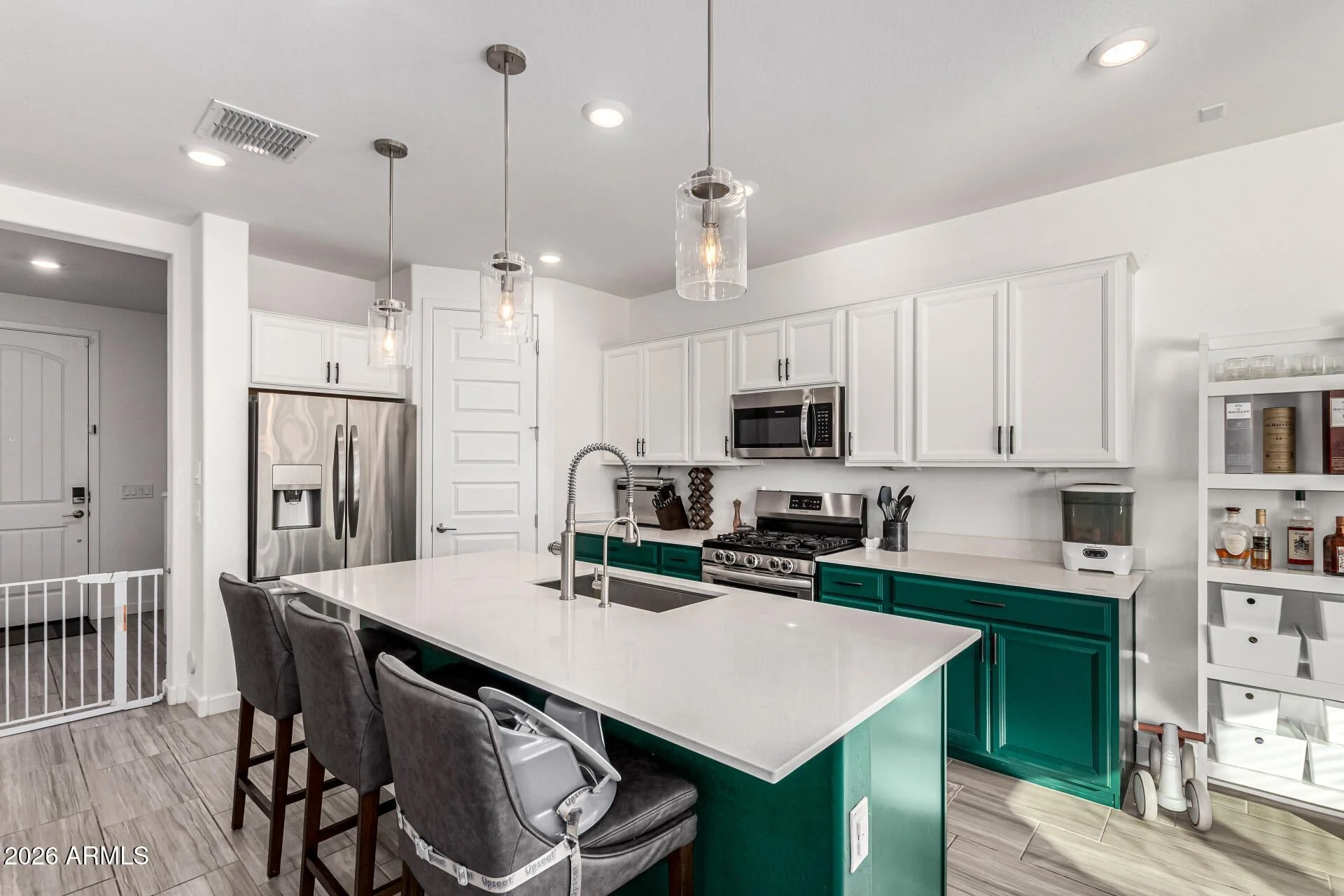 Modern kitchen in a Chandler, Arizona home for sale featuring quartz countertops, large center island, gas range, walk-in pantry, and contemporary cabinetry