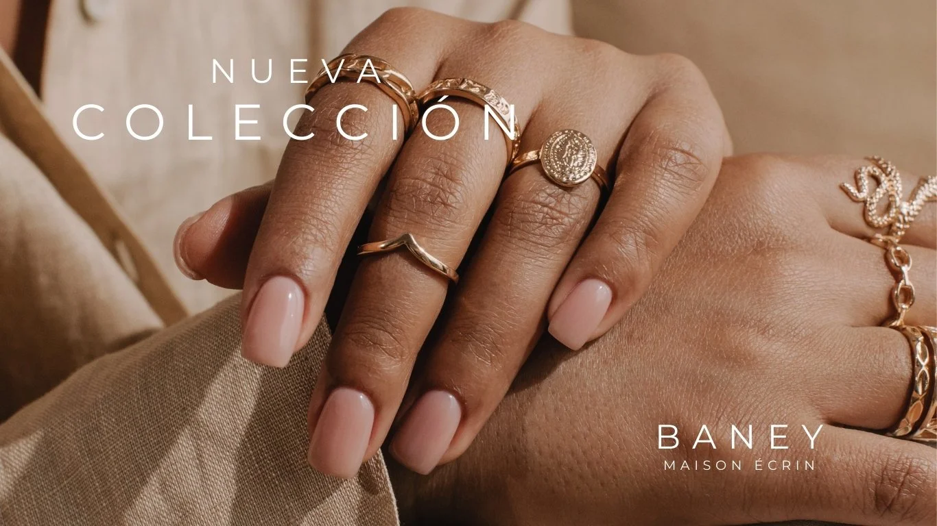 Mano con varias alianzas y anillos de oro, mostrando la colección de joyería de la marca Baney Maison Écrin.