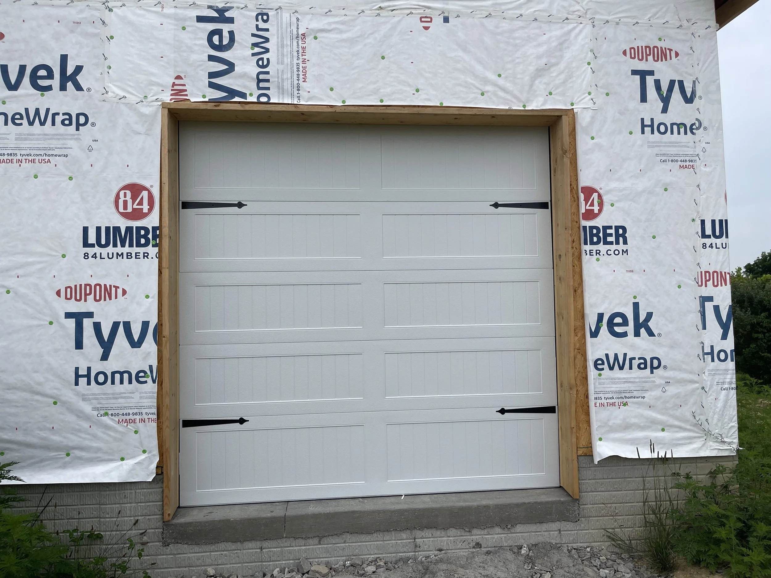 White 8 foot garage door with 2 black steel aesthetic hardware accents on each side