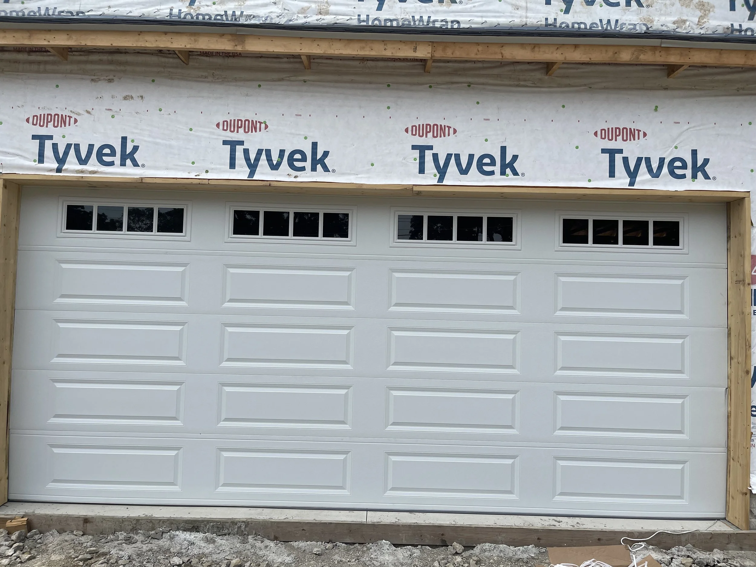 White 18 foot garage door white 5 sections. Top section contains 4 windows across the length of the door