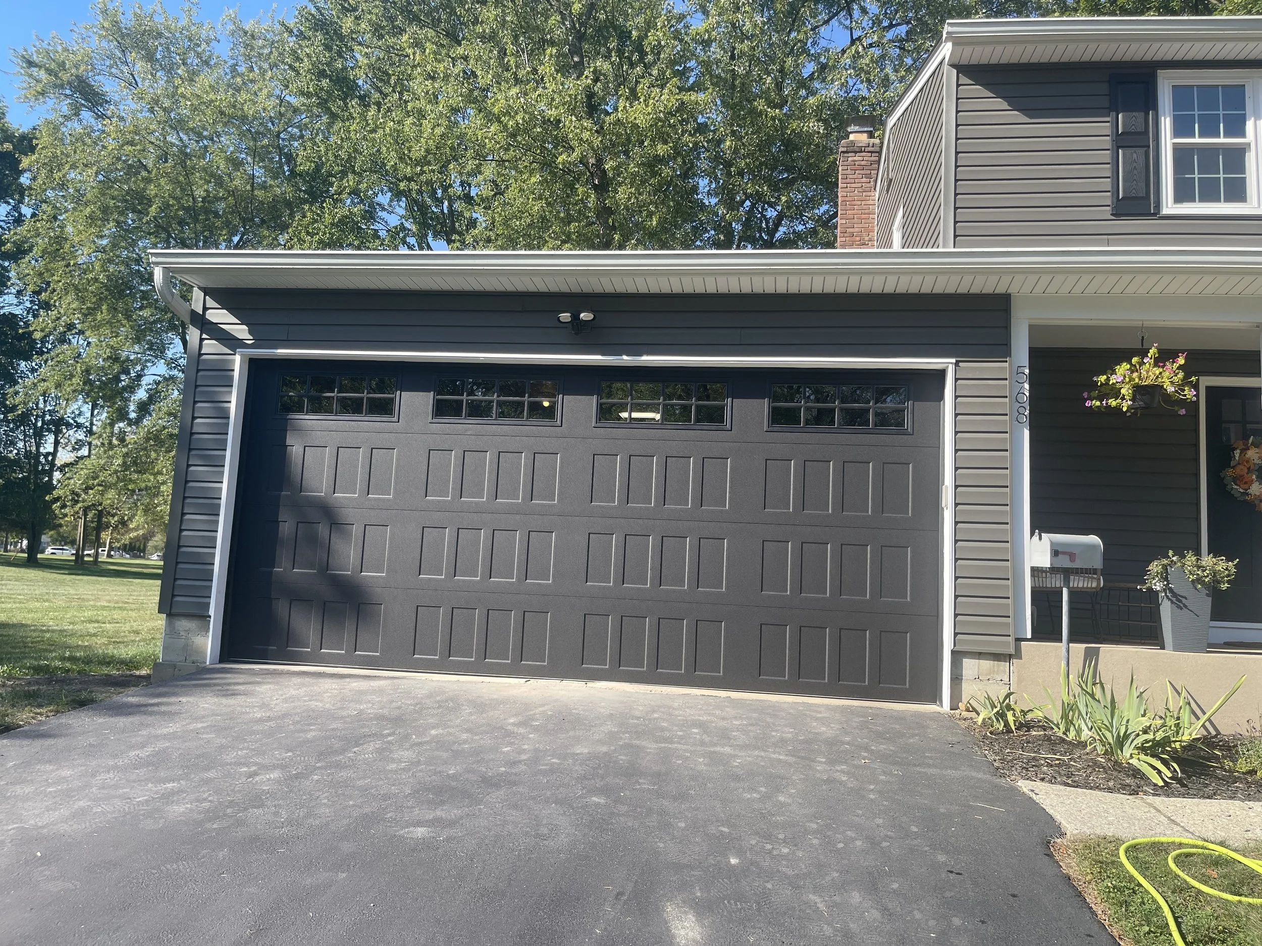 Black 18 foot garage door with four windows in the top section. Each window is separated into 4 parts