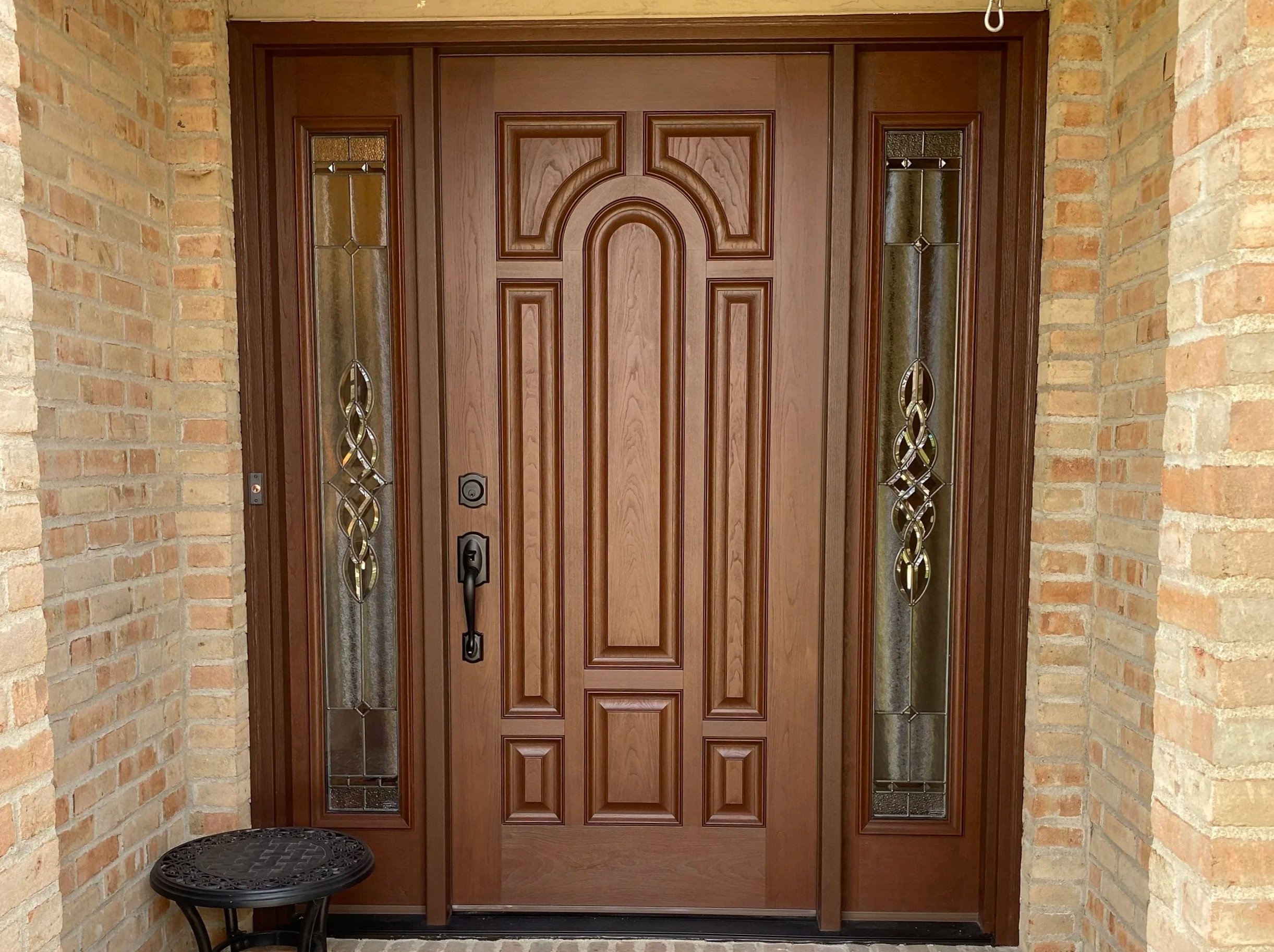 A brick exterior of an entryway. Centered is a wood man door with two sidelights