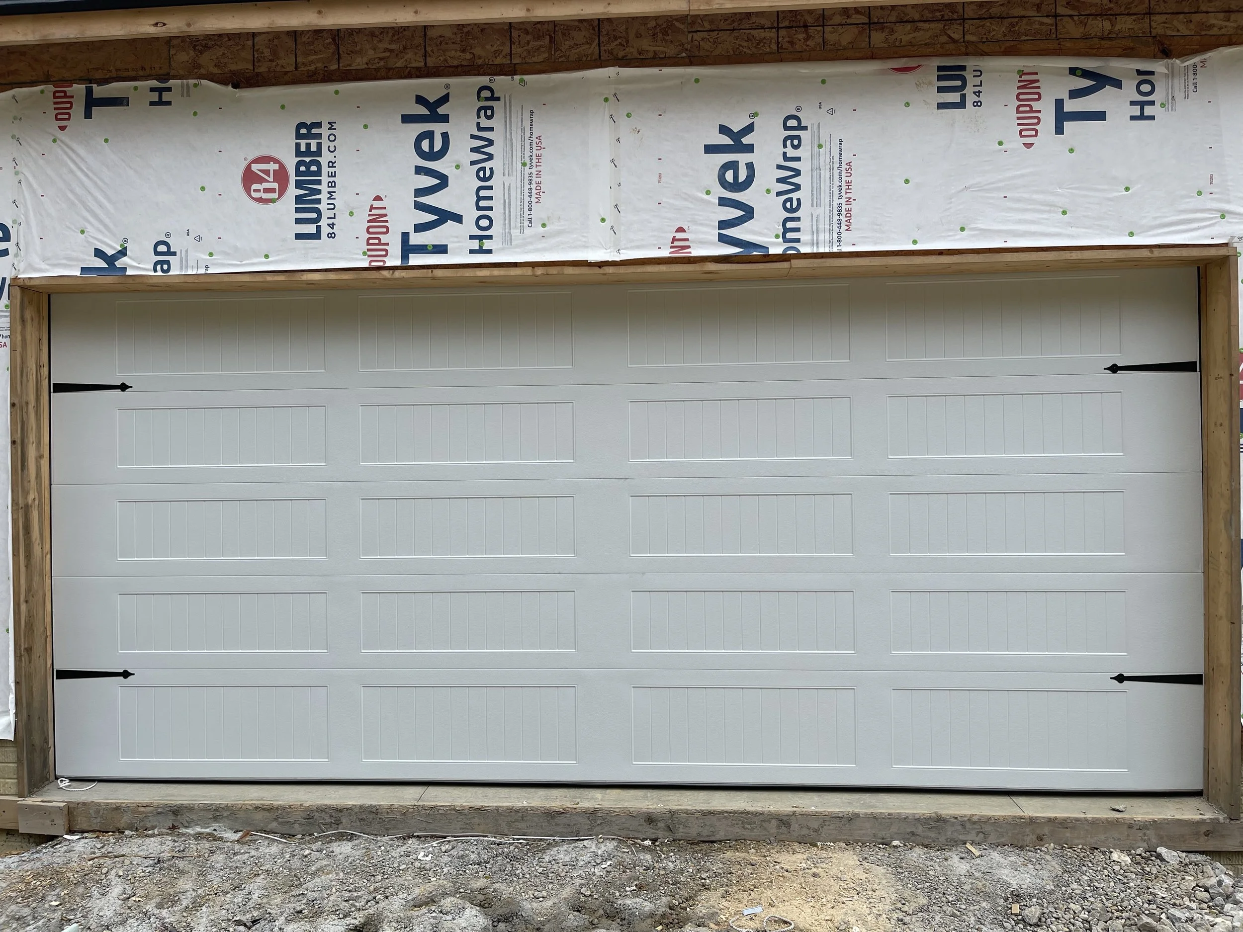 White 18 foot garage door with 2 black steel aesthetic hardware accents on each side