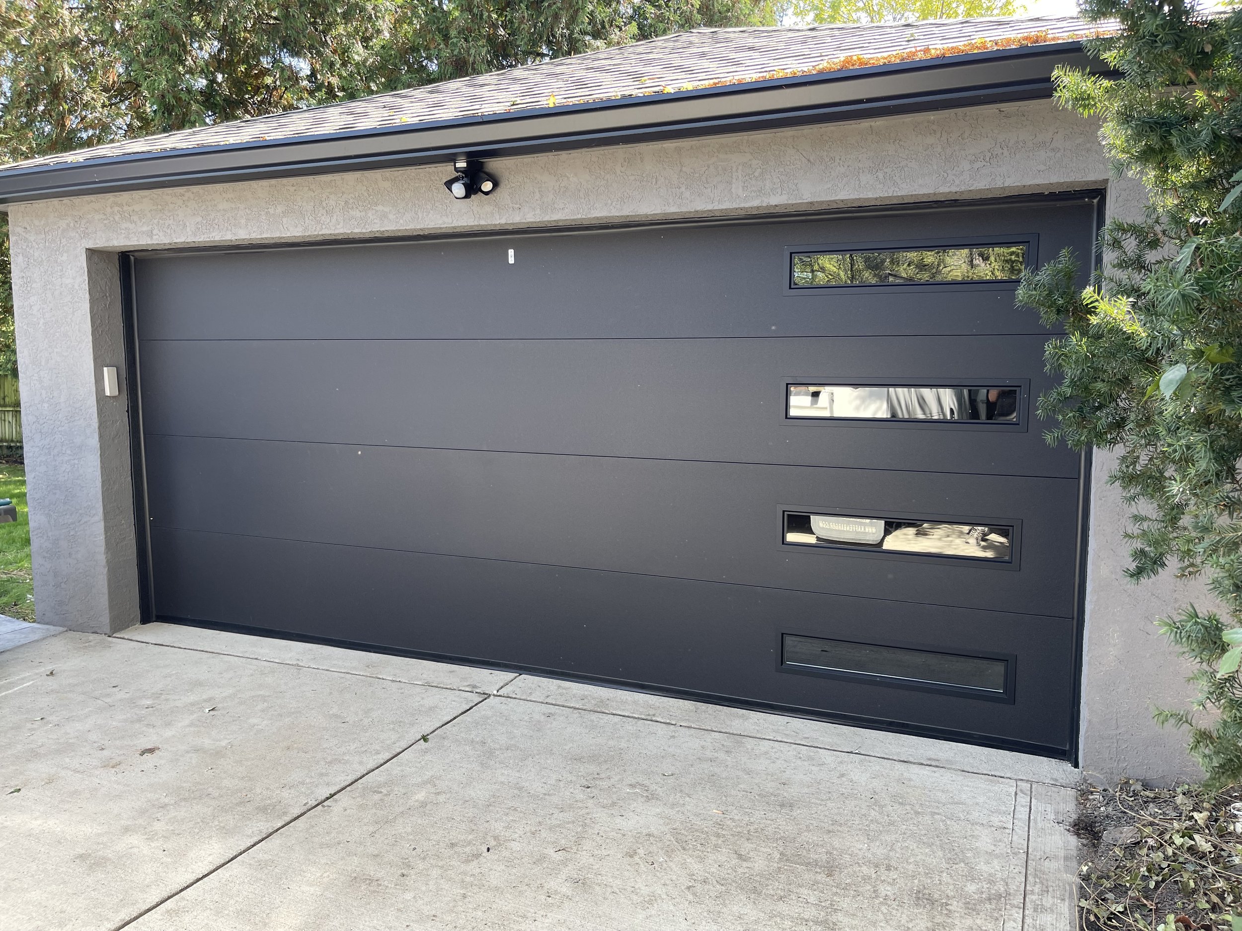 A faded image of a black 18-by-8 foot garage door with windows on the right side in all sections