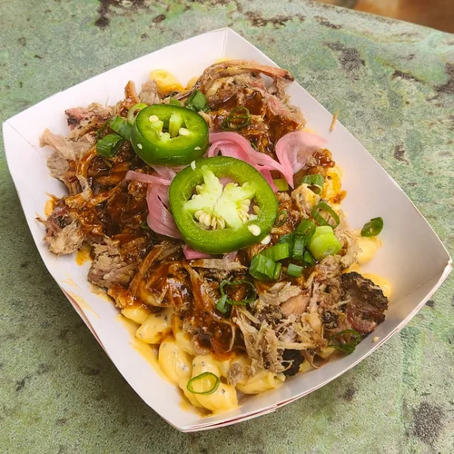 Loaded mac and cheese boat topped with pulled pork, jalapeño and pickled onion