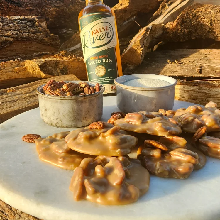 Pecan pralines cooling next to a bottle of False River spiced rum