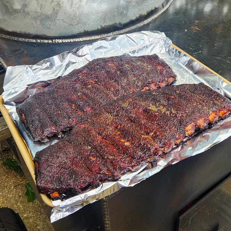 Two racks of glazed spare ribs resting on foil