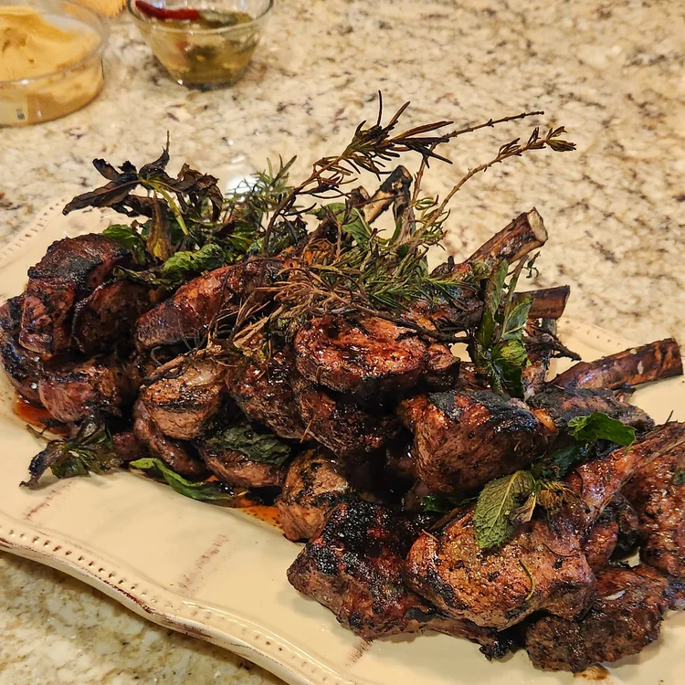 A pile of charred lamb chops with fresh herbs
