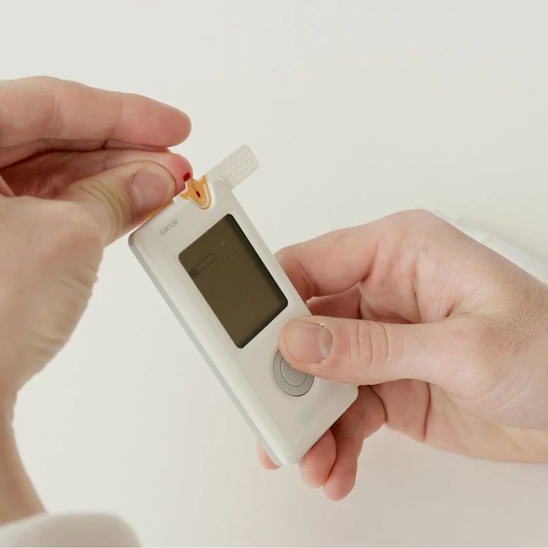 Person inserting a test strip into a glucometer for blood sugar testing.
