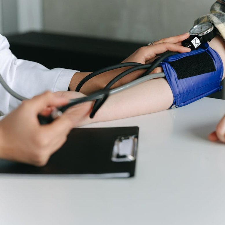 A healthcare professional measuring a patient's blood pressure using a cuff and sphygmomanometer.