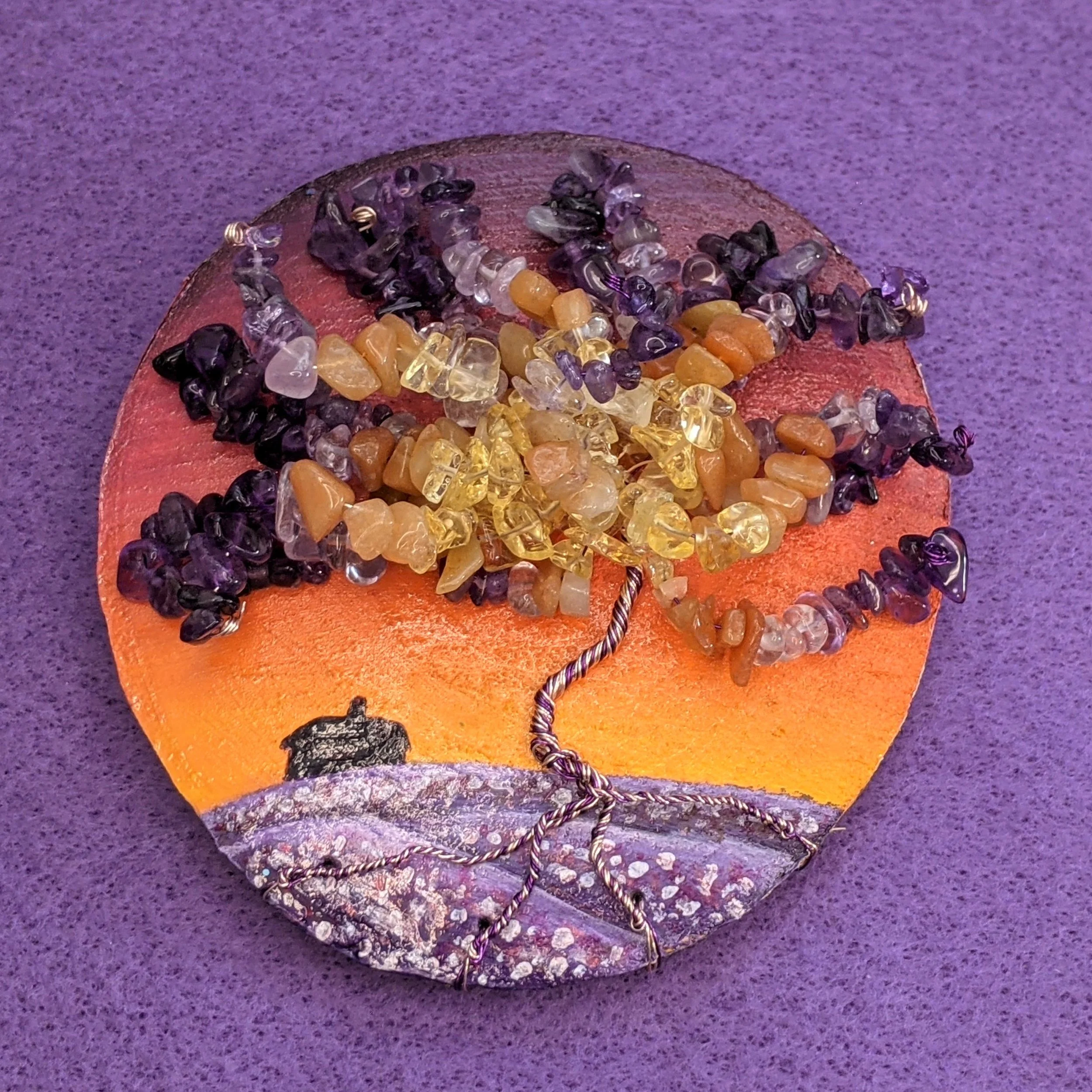 Painting of an orange sunset over a field of lavender on a wood slice, with a wire and gemstone tree