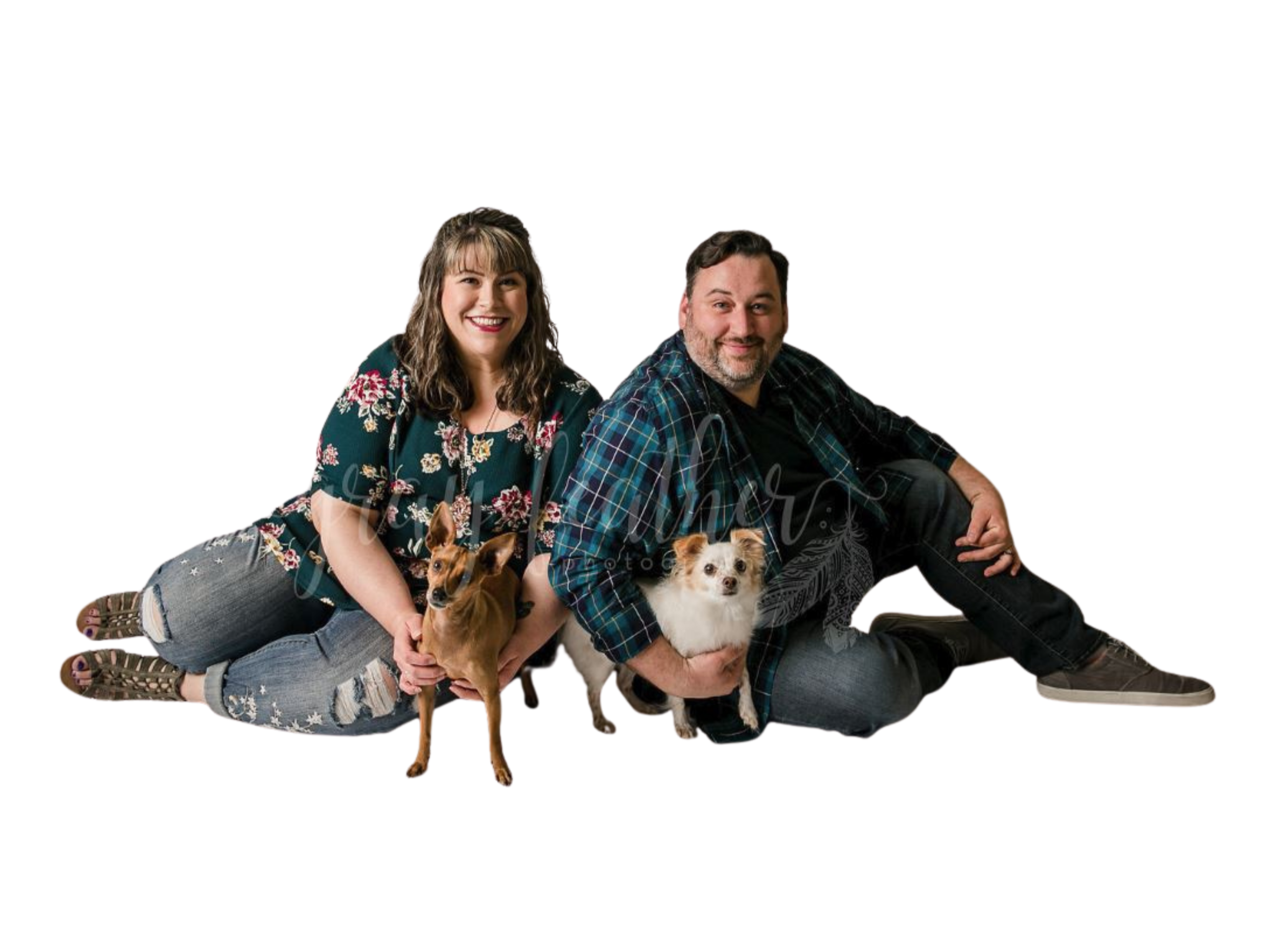 A woman and a man lying on the floor with two dogs, one small brown dog and one small white and brown dog, against a plain white background.