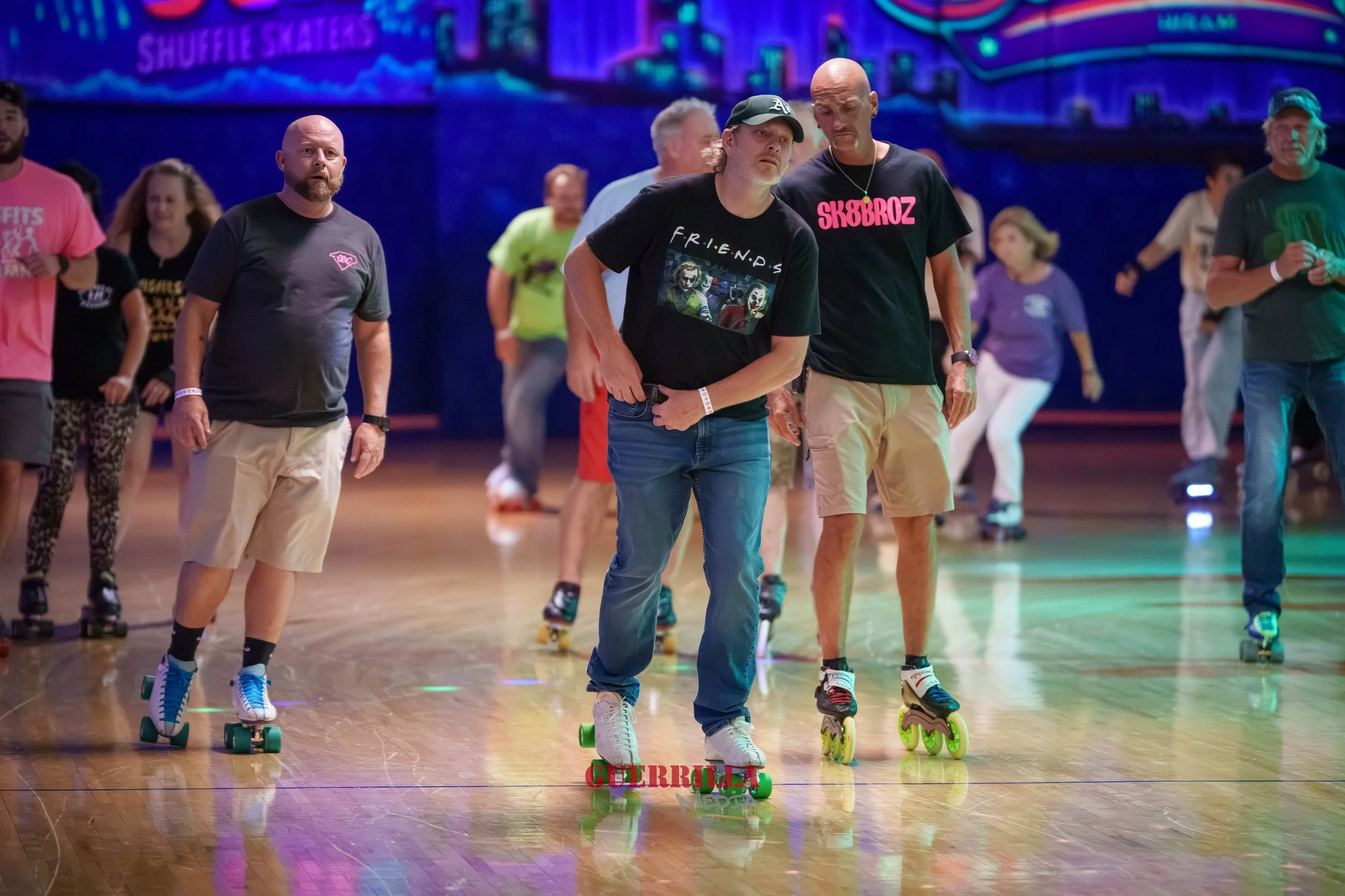 People roller skating at an indoor roller rink with colorful lights and a neon sign in the background.