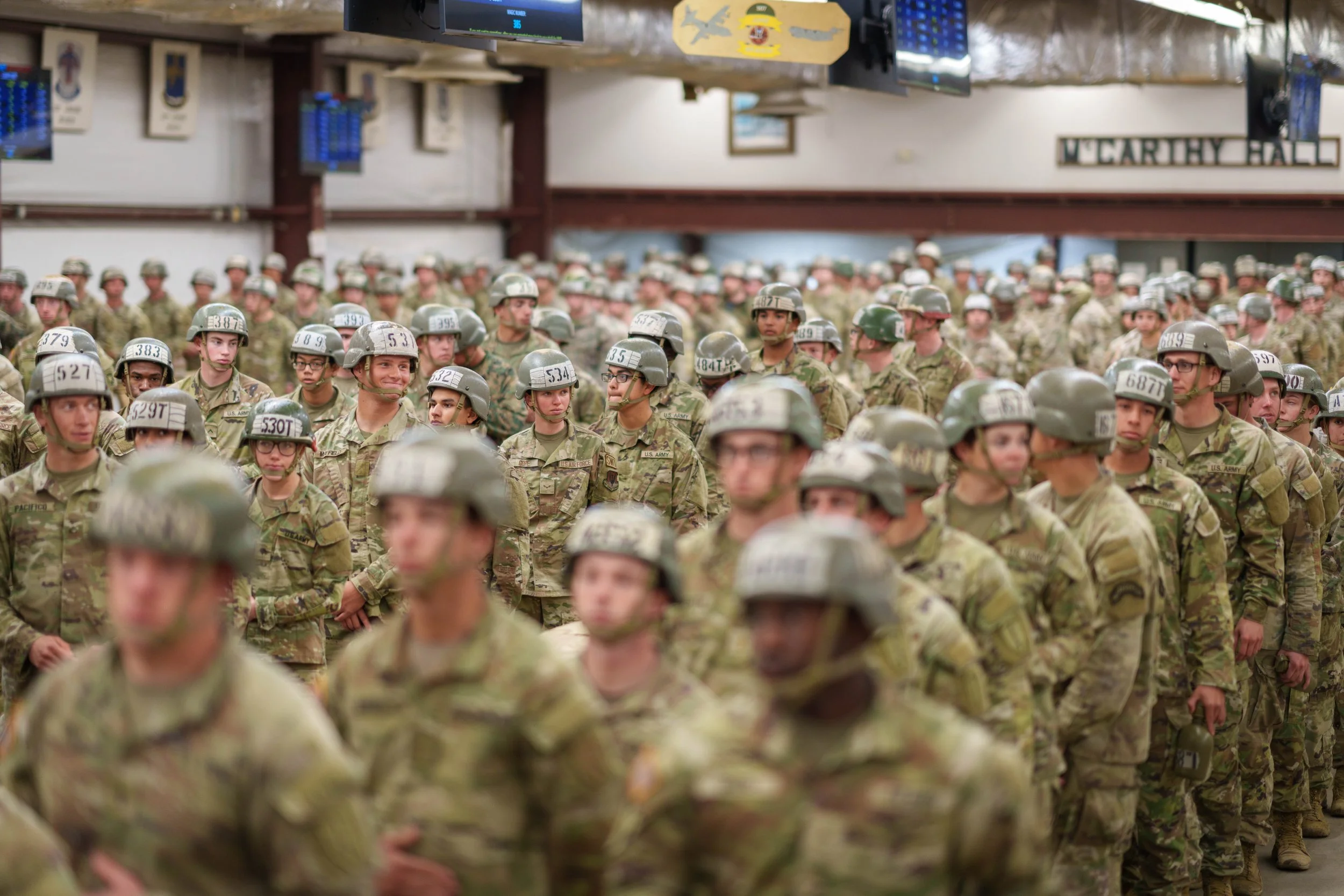 A large group of soldiers in uniform standing in formation inside a building.