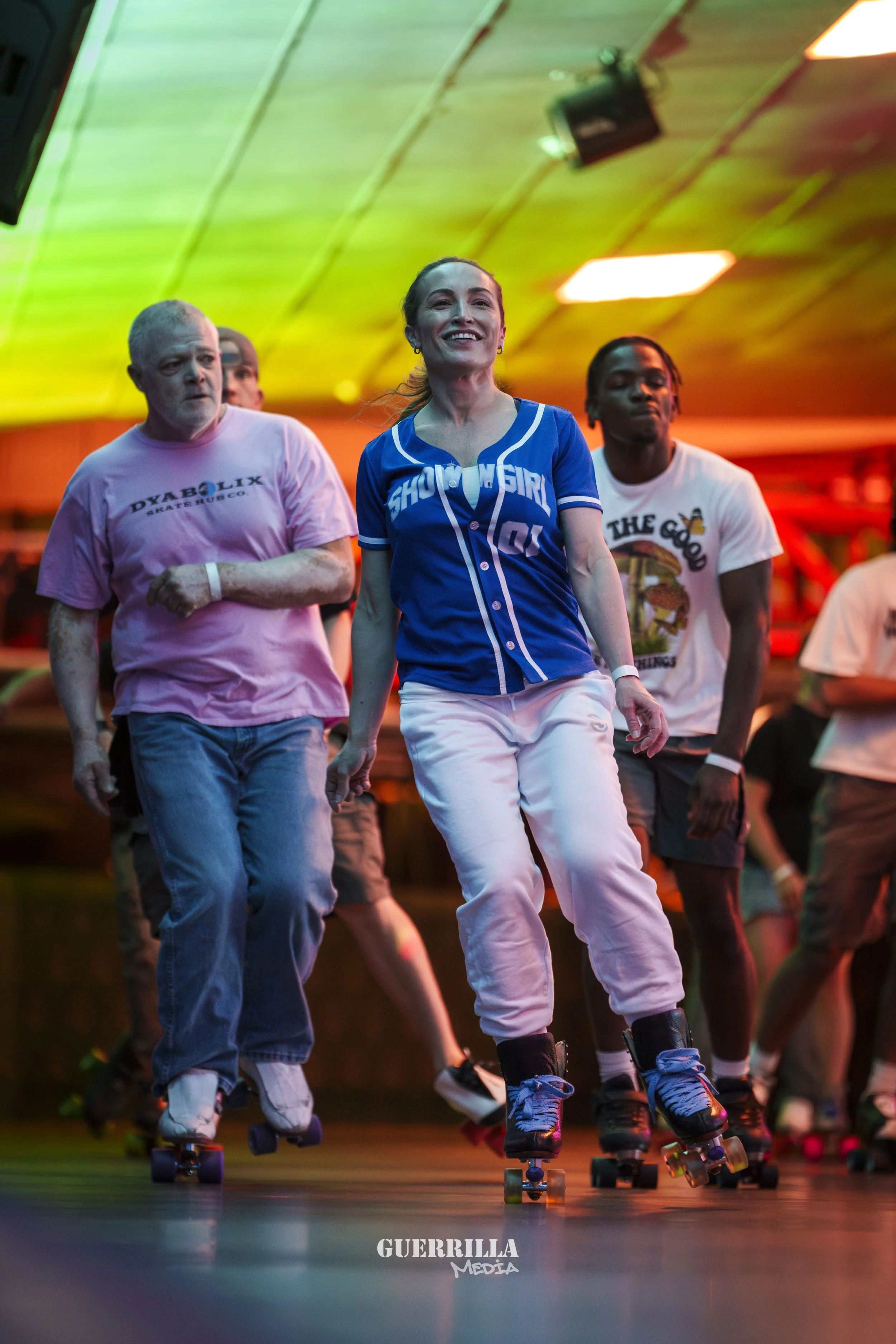 People roller skating indoors with colorful lighting.