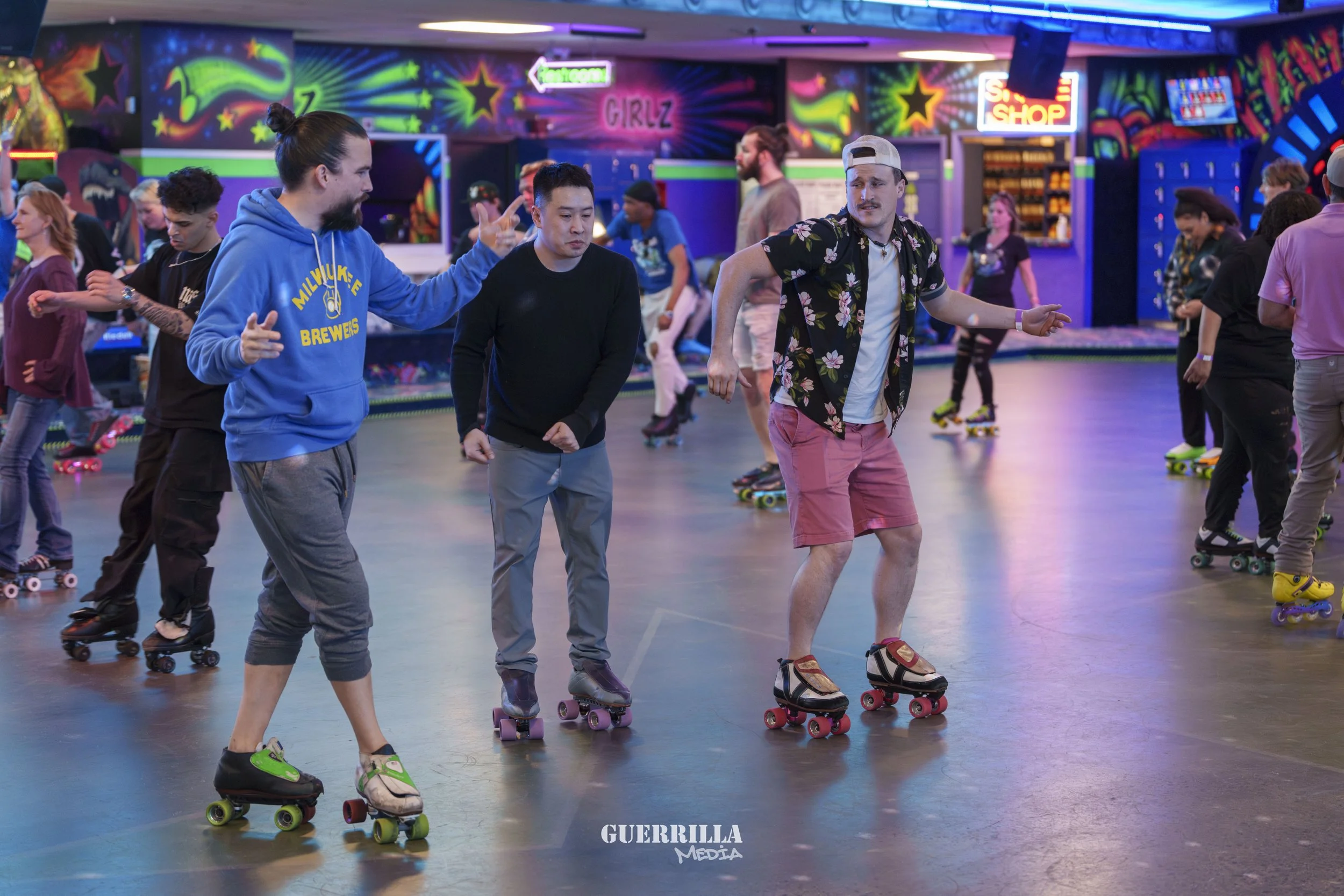 People roller skating on a rink with colorful neon lights and graffiti-style decorations in the background.