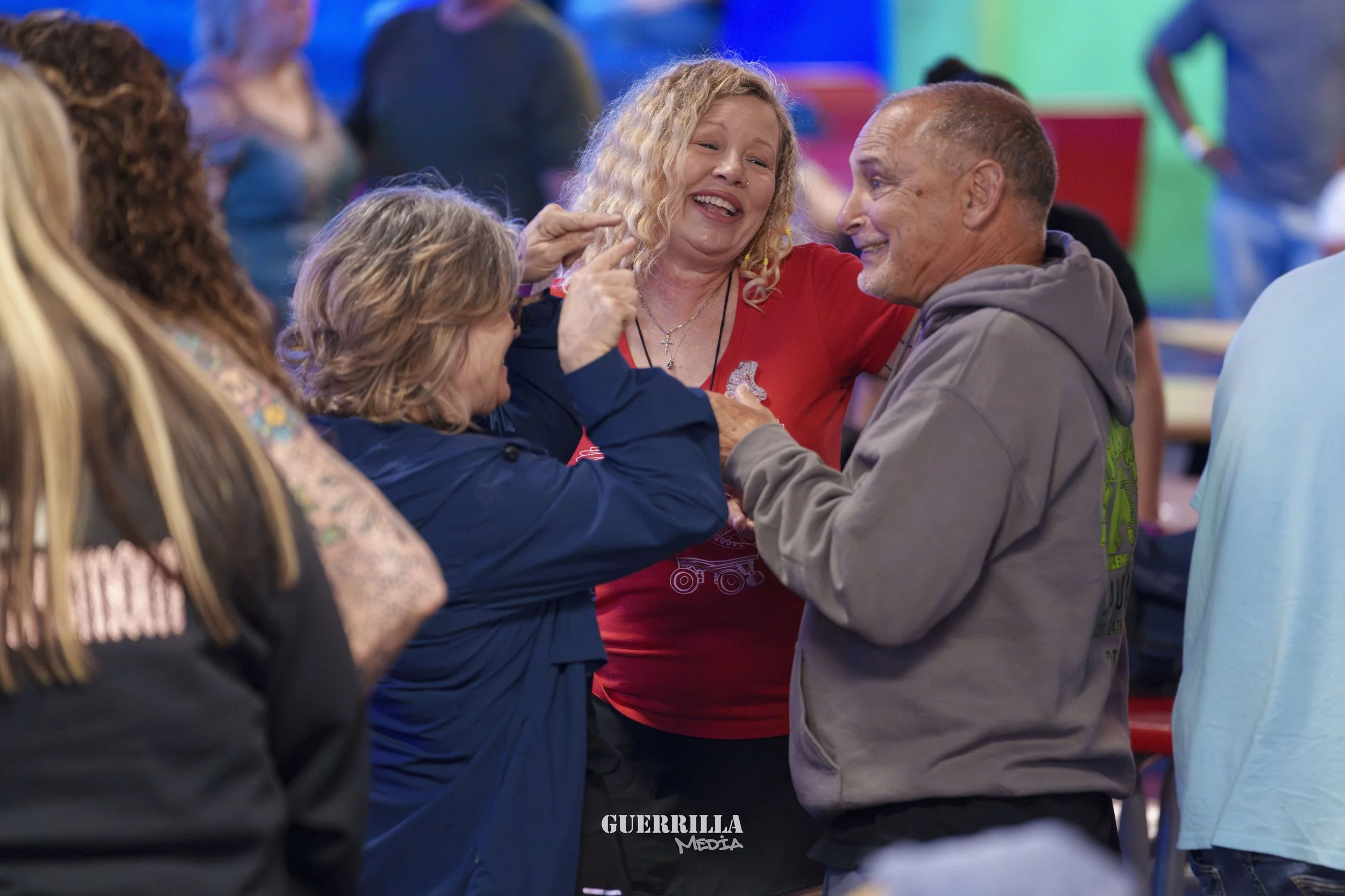 Group of people laughing and smiling together at social gathering with colorful background.