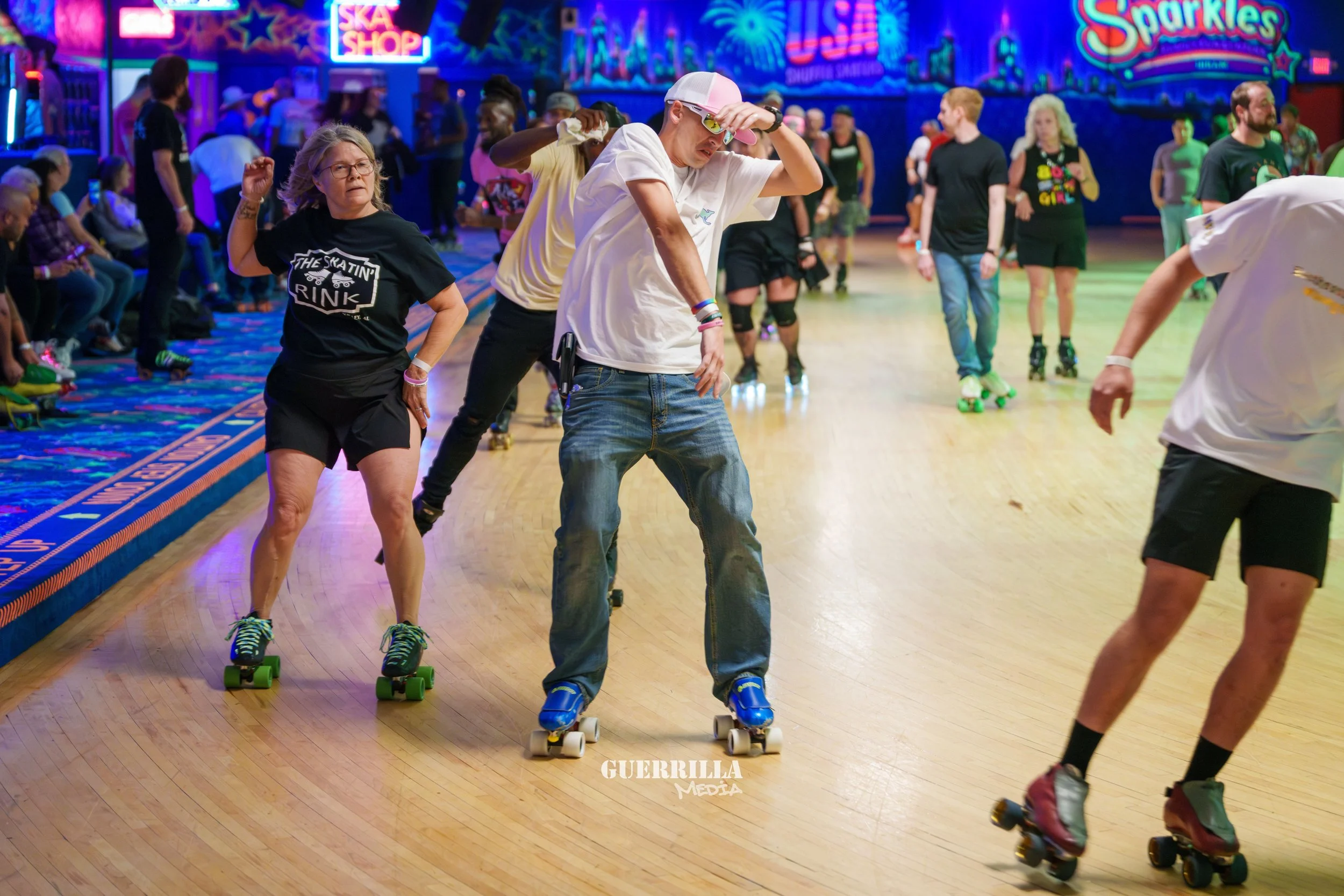 People roller skating at an indoor skating rink with bright neon lights and colorful signs in the background.