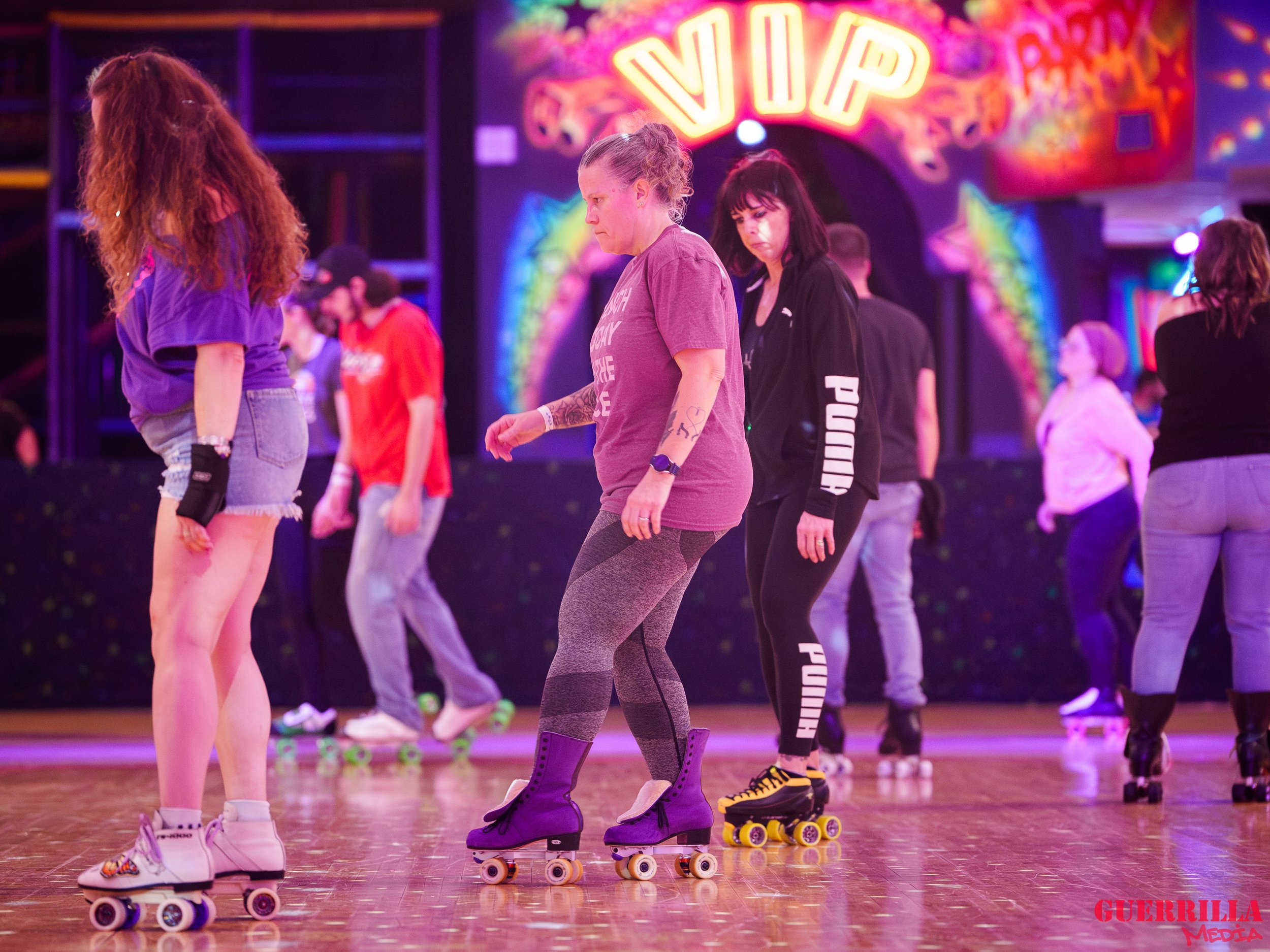 People roller skating in a rink with colorful lights and a vibrant background.