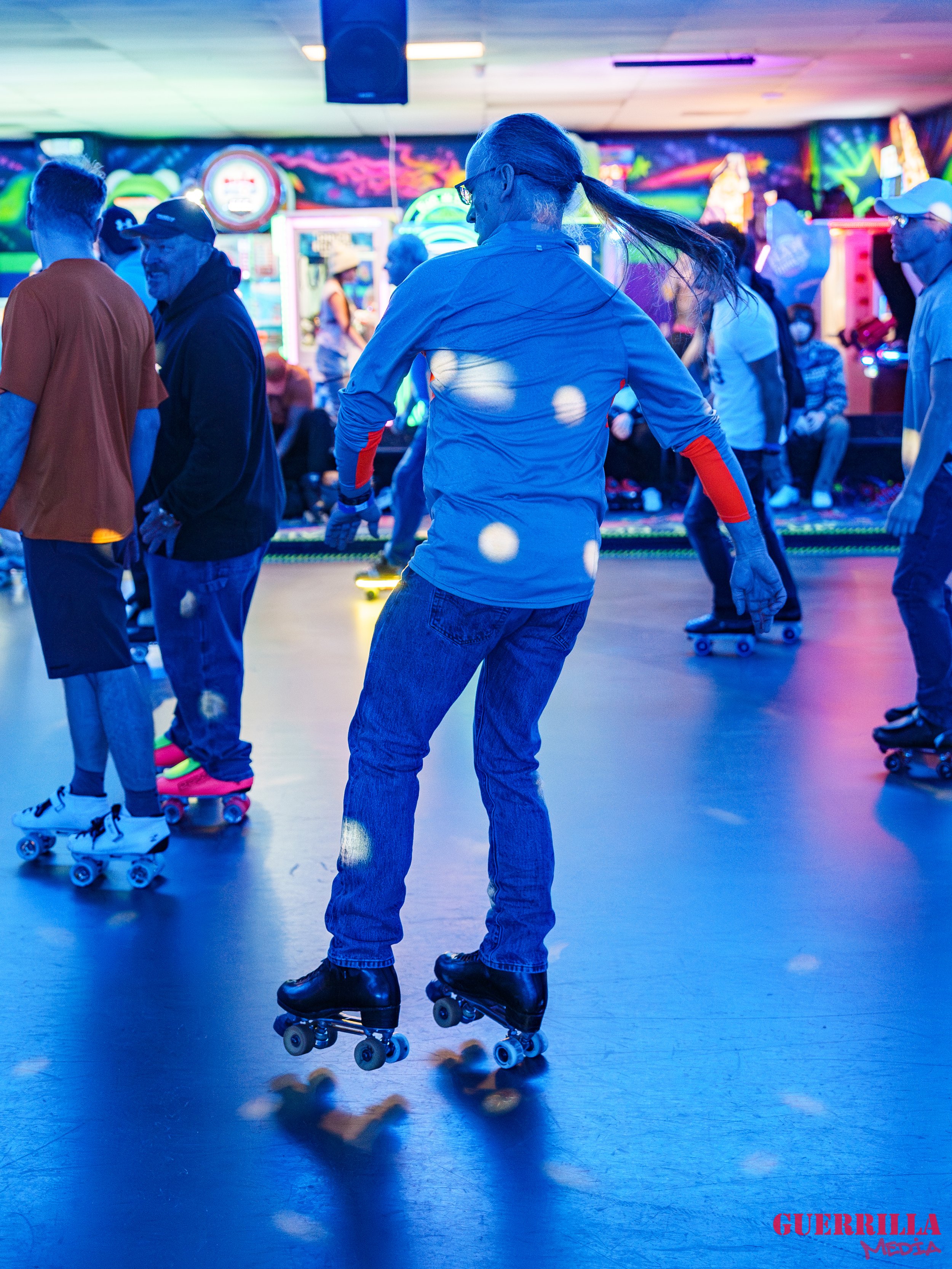 People roller skating inside an arcade or skating rink with colorful neon lights and decorations.