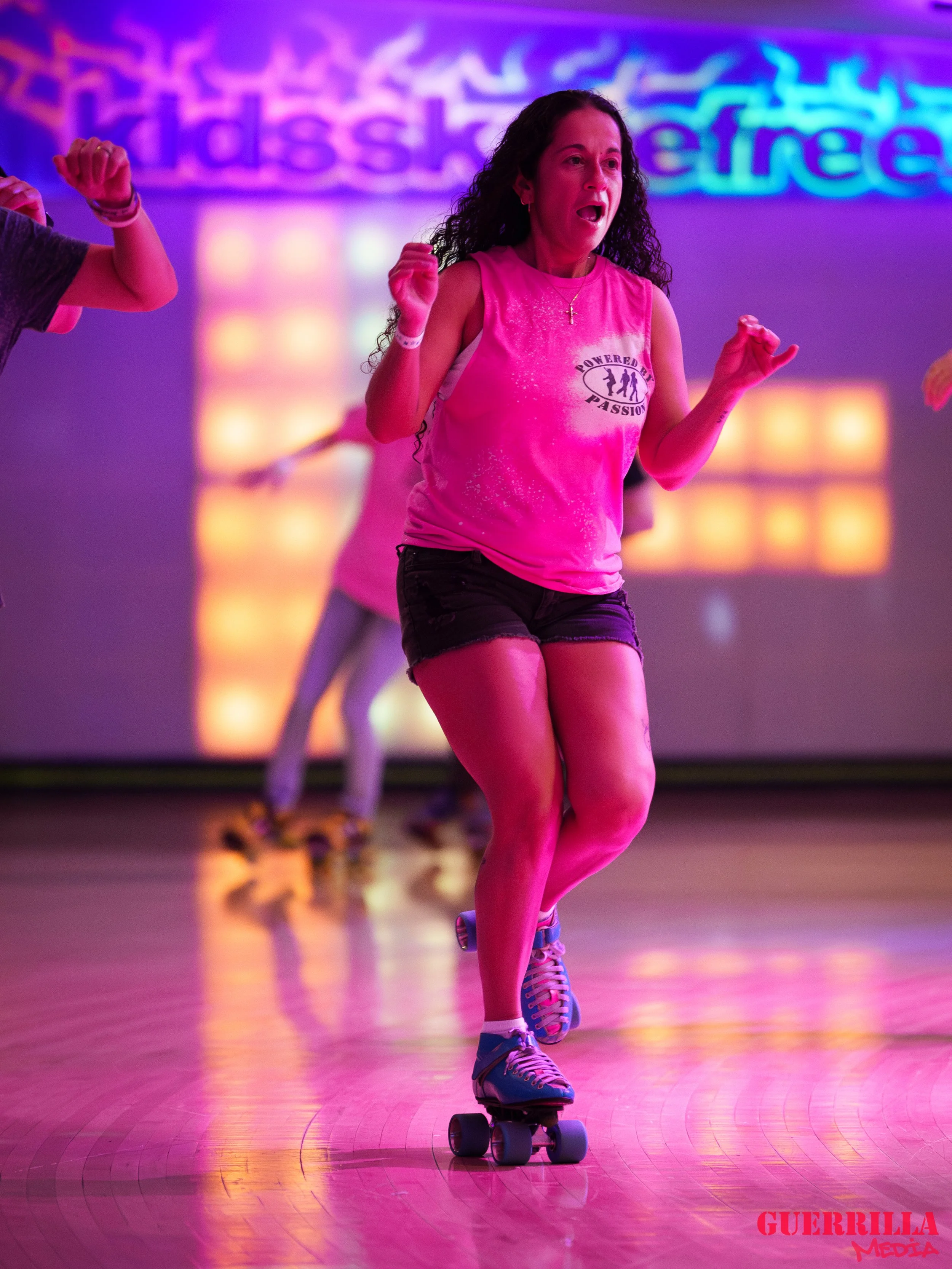 Woman roller skating indoors with colorful neon lights and a backdrop reading 'dance' and 'freestyle'.