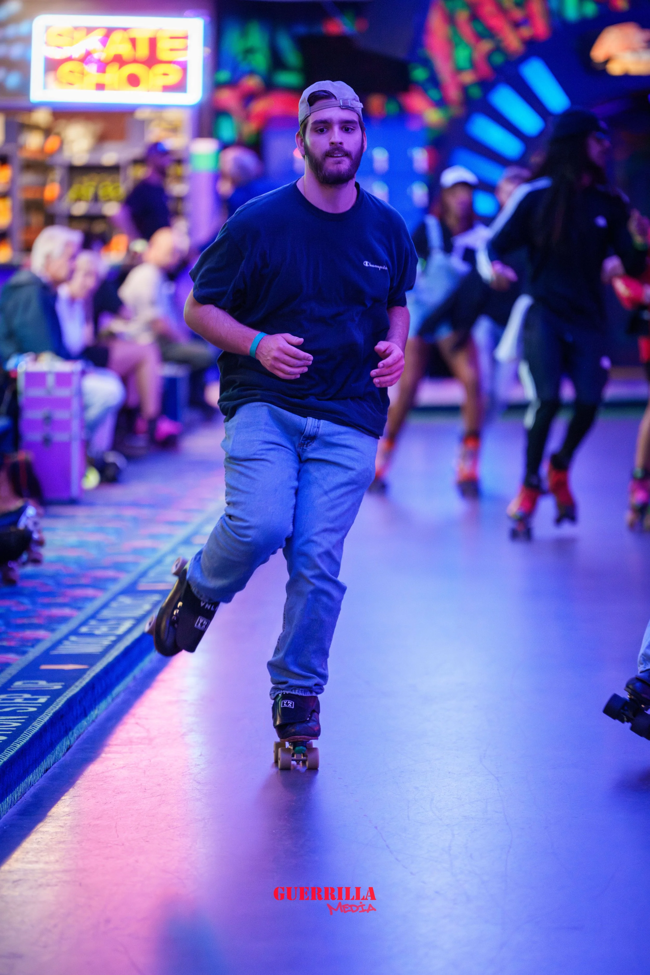 A man rollerblading on a roller rink with colorful neon lights, surrounded by other skaters and spectators, with a sign that reads 'Skate Shop' in the background.