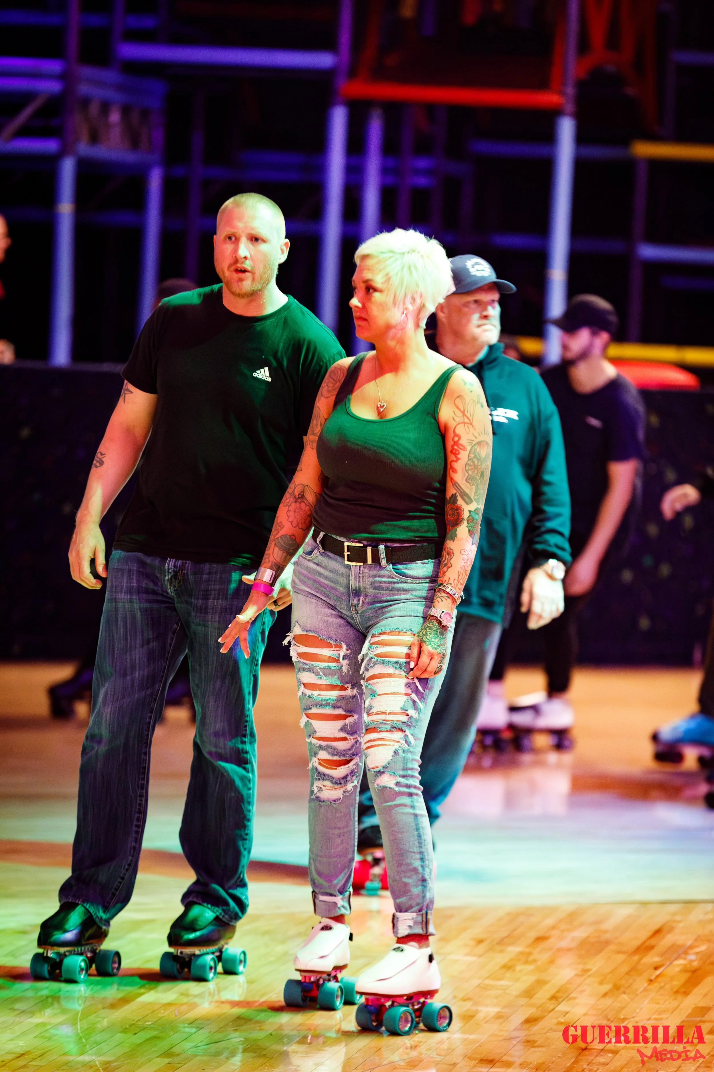 People roller skating indoors under colorful lighting at a skate rink.