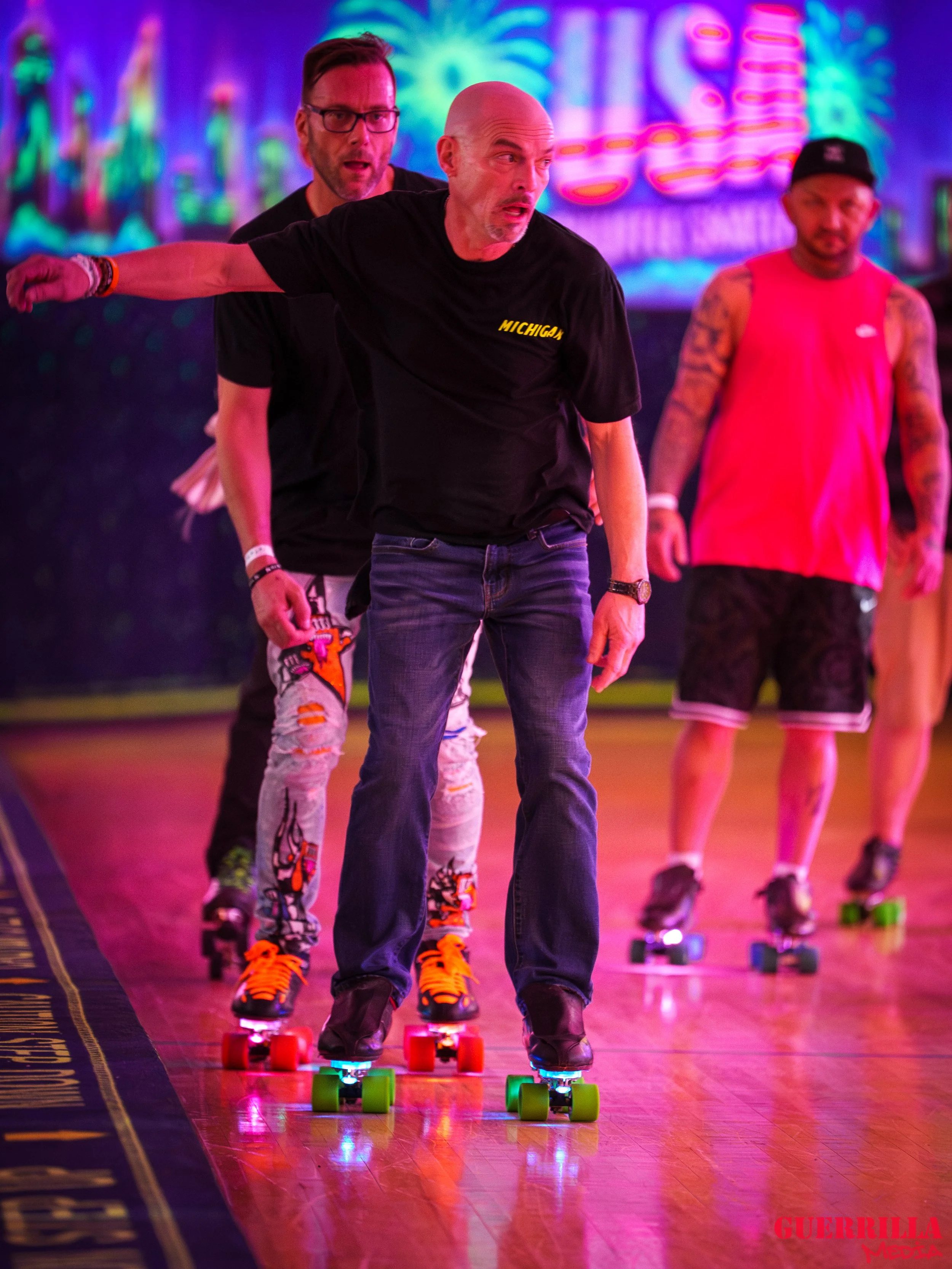 Four people skating on a roller rink with colorful neon lighting.