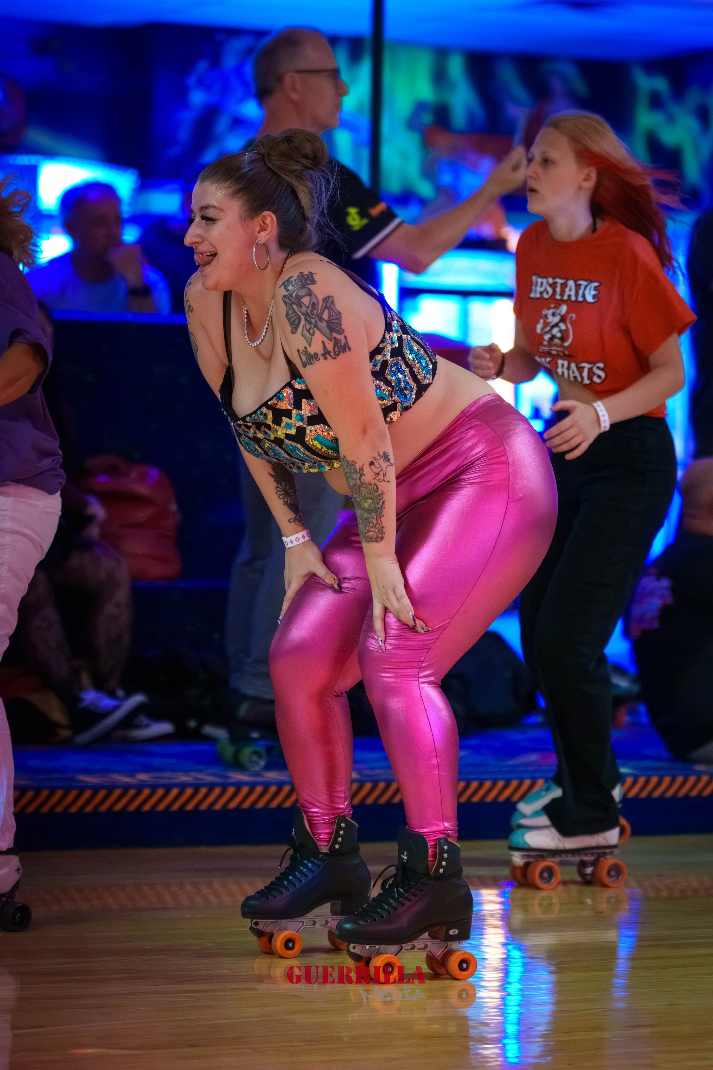 Woman roller skating in colorful attire, leaning forward and smiling, with other skaters and neon-lit background.