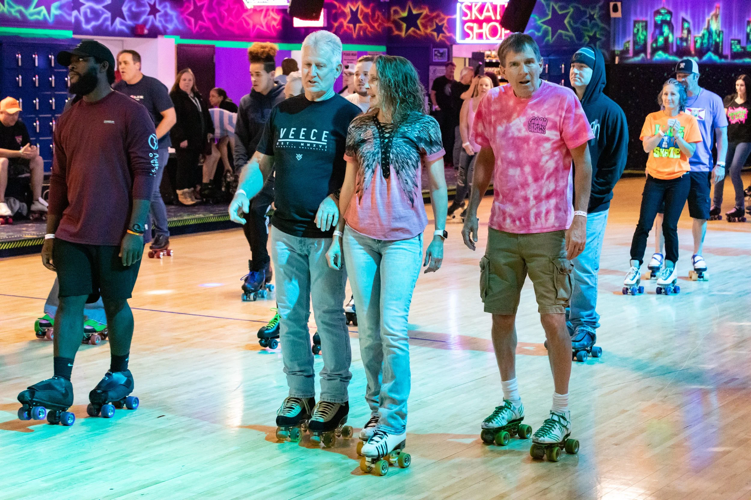 People roller skating in a roller rink with neon star decorations on the walls.