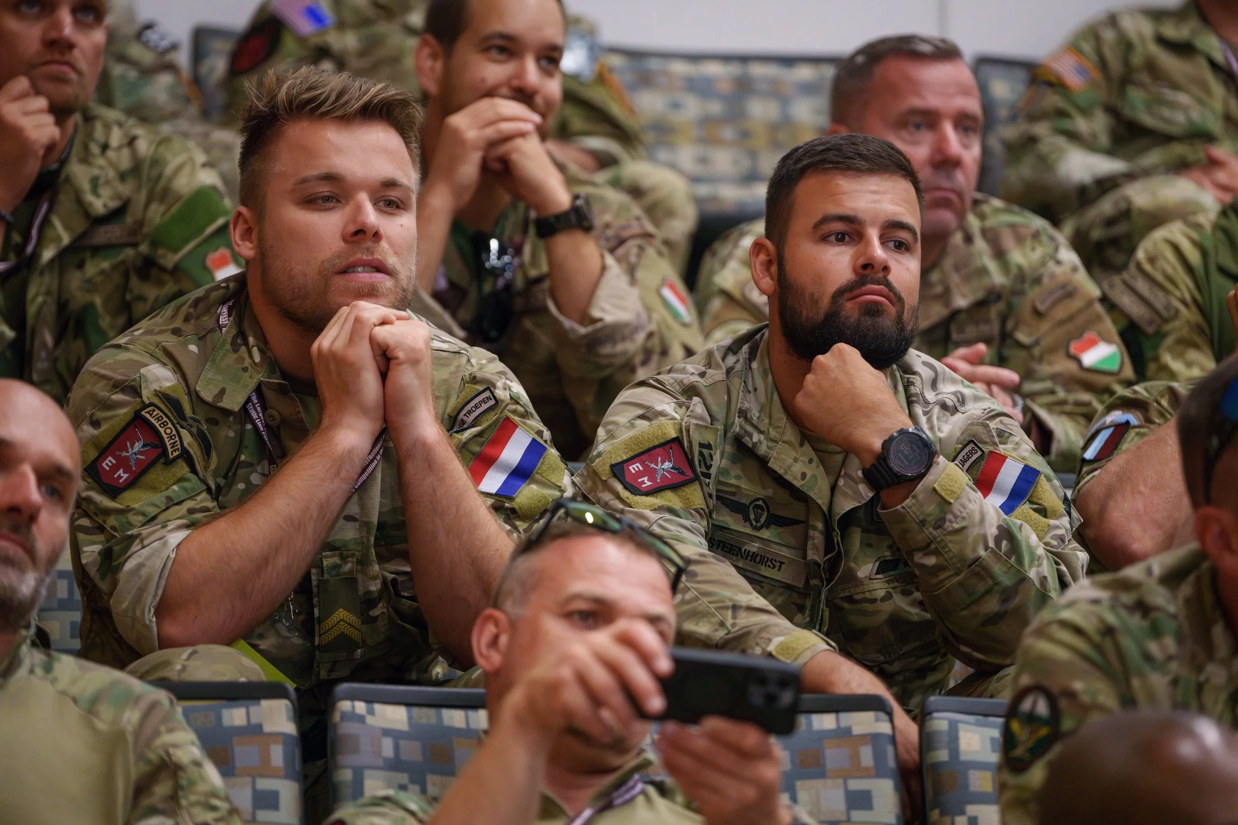 Military personnel in uniform sitting and attentively listening in a conference or briefing room.