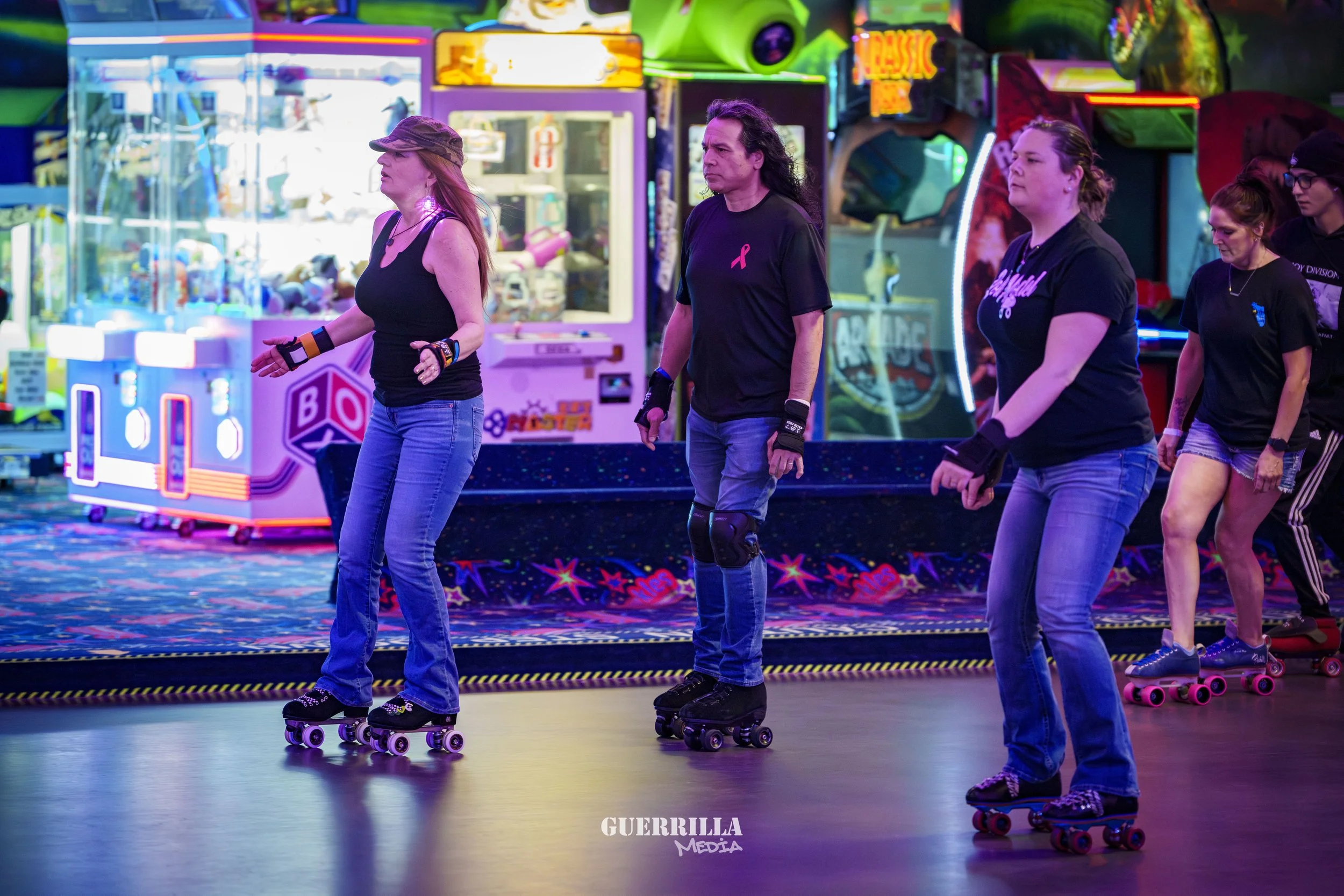 A group of women roller skating in an indoor arcade with colorful lights and gaming machines in the background.