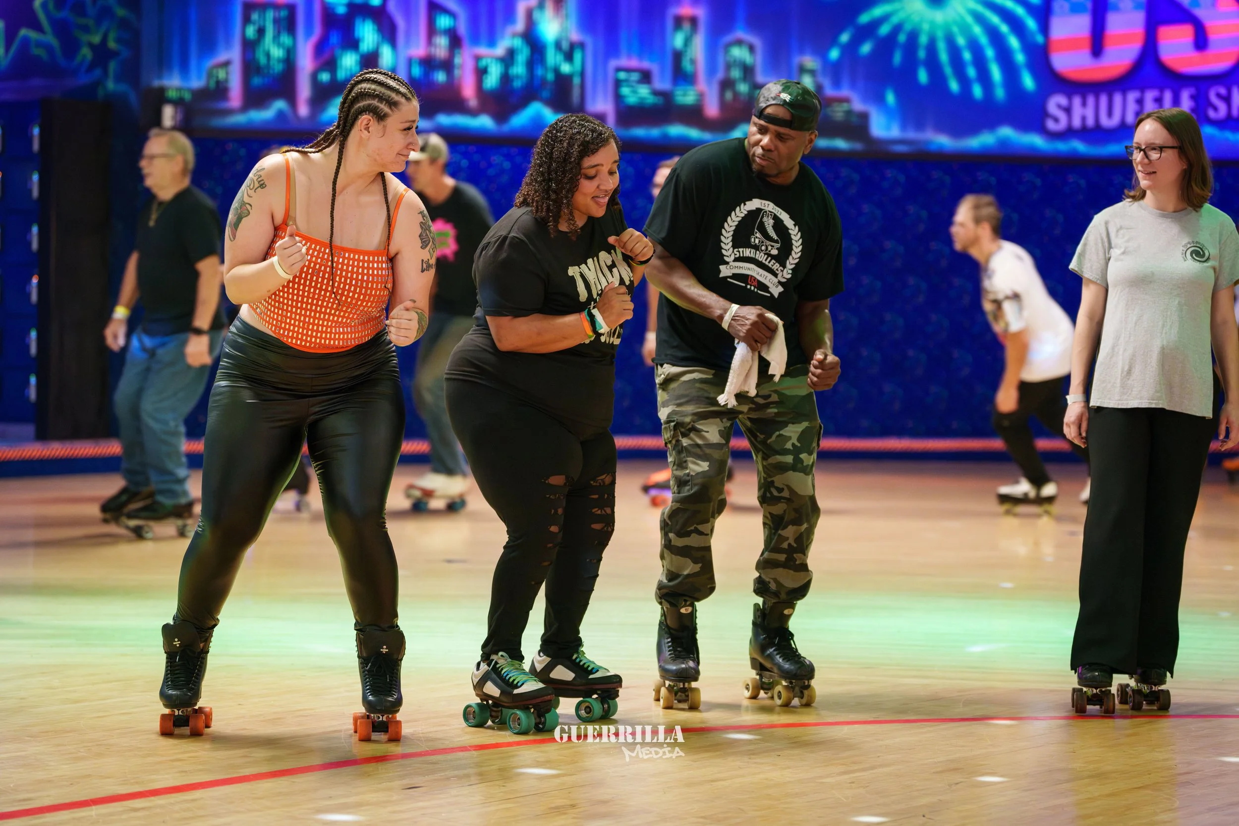 Group of people roller skating on an indoor rink, enjoying and socializing, with a colorful cityscape background on a large digital screen.