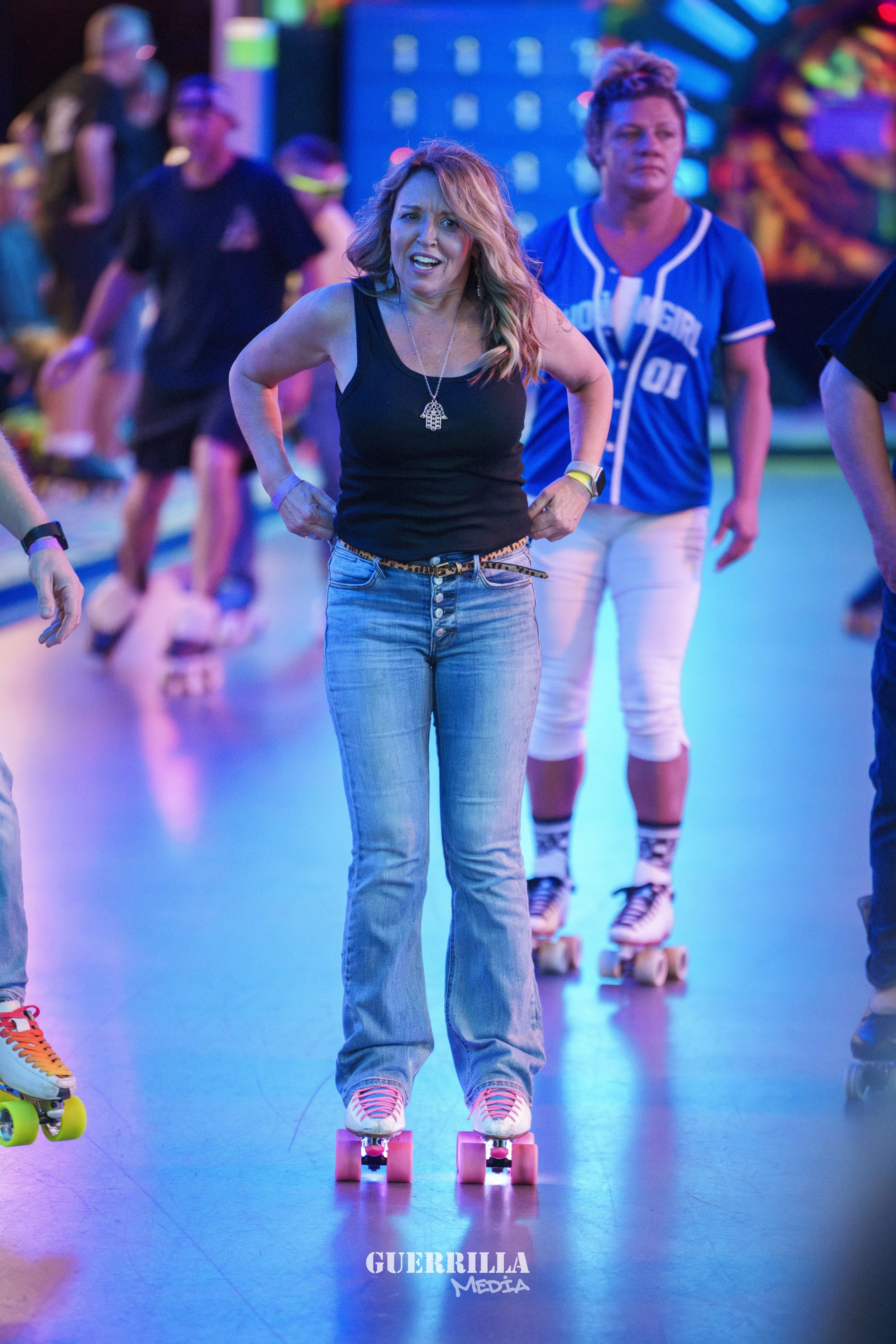 People roller skating at an indoor rink with colorful neon lights.