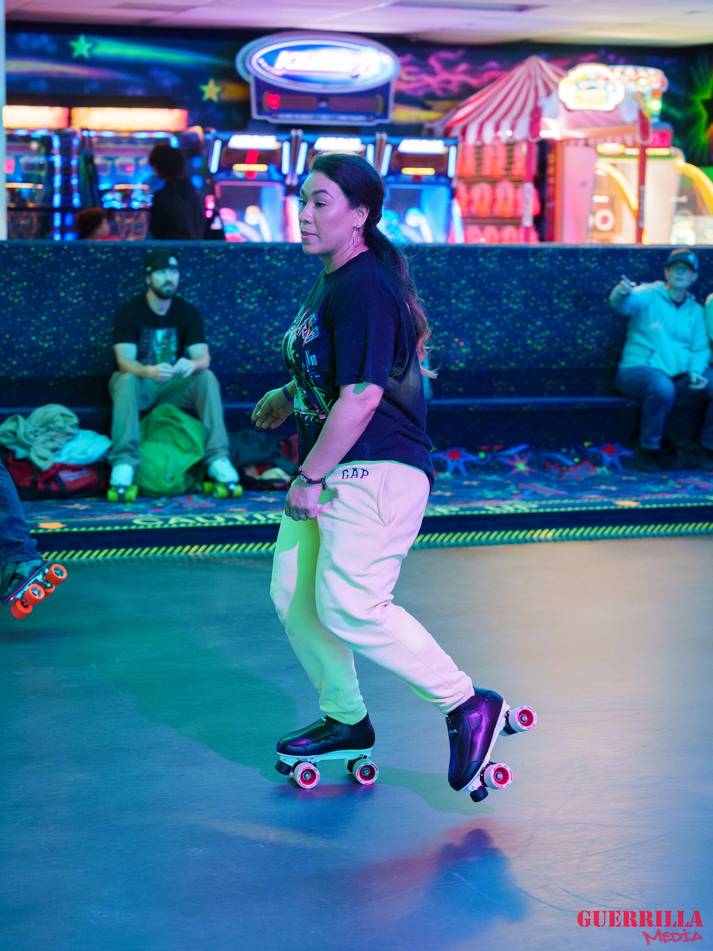 A woman roller skating at an arcade with neon lights and a carnival tent in the background.