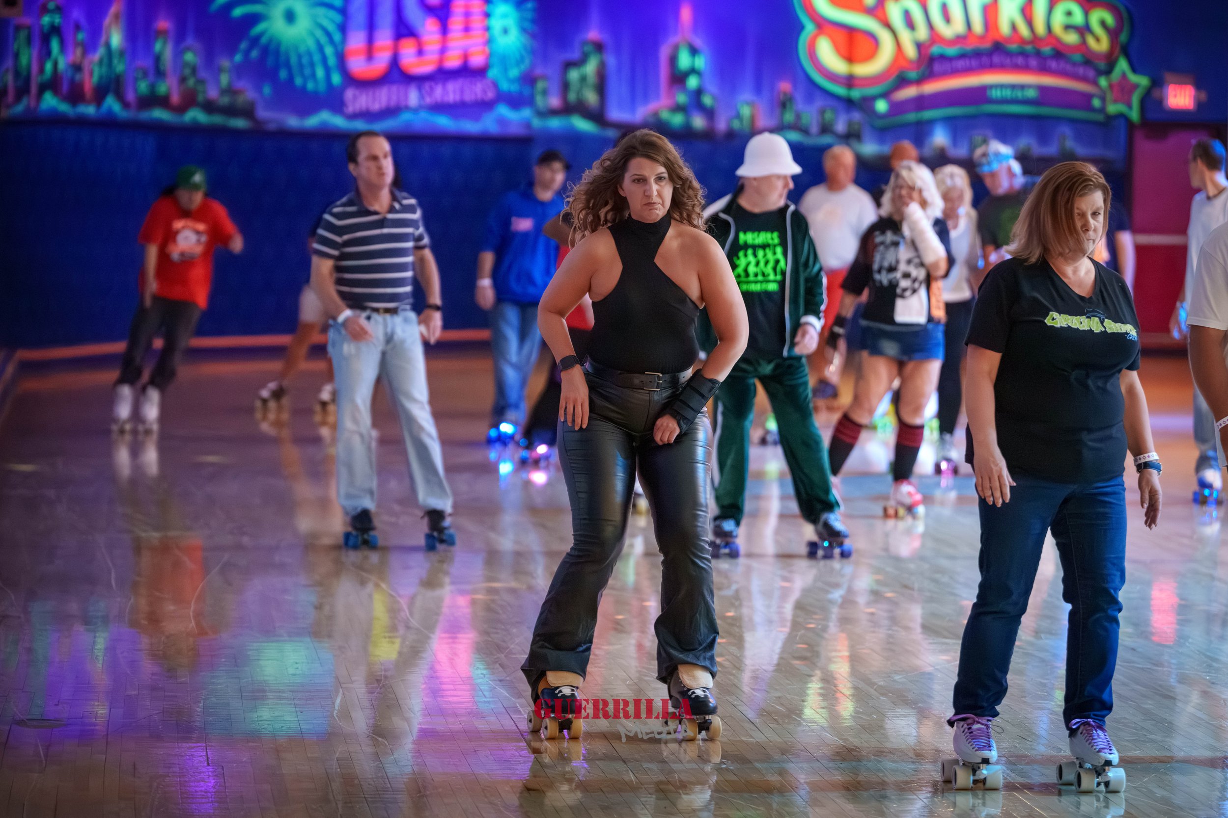 People roller skating in an indoor rink with colorful neon neon signboards and vibrant lighting.