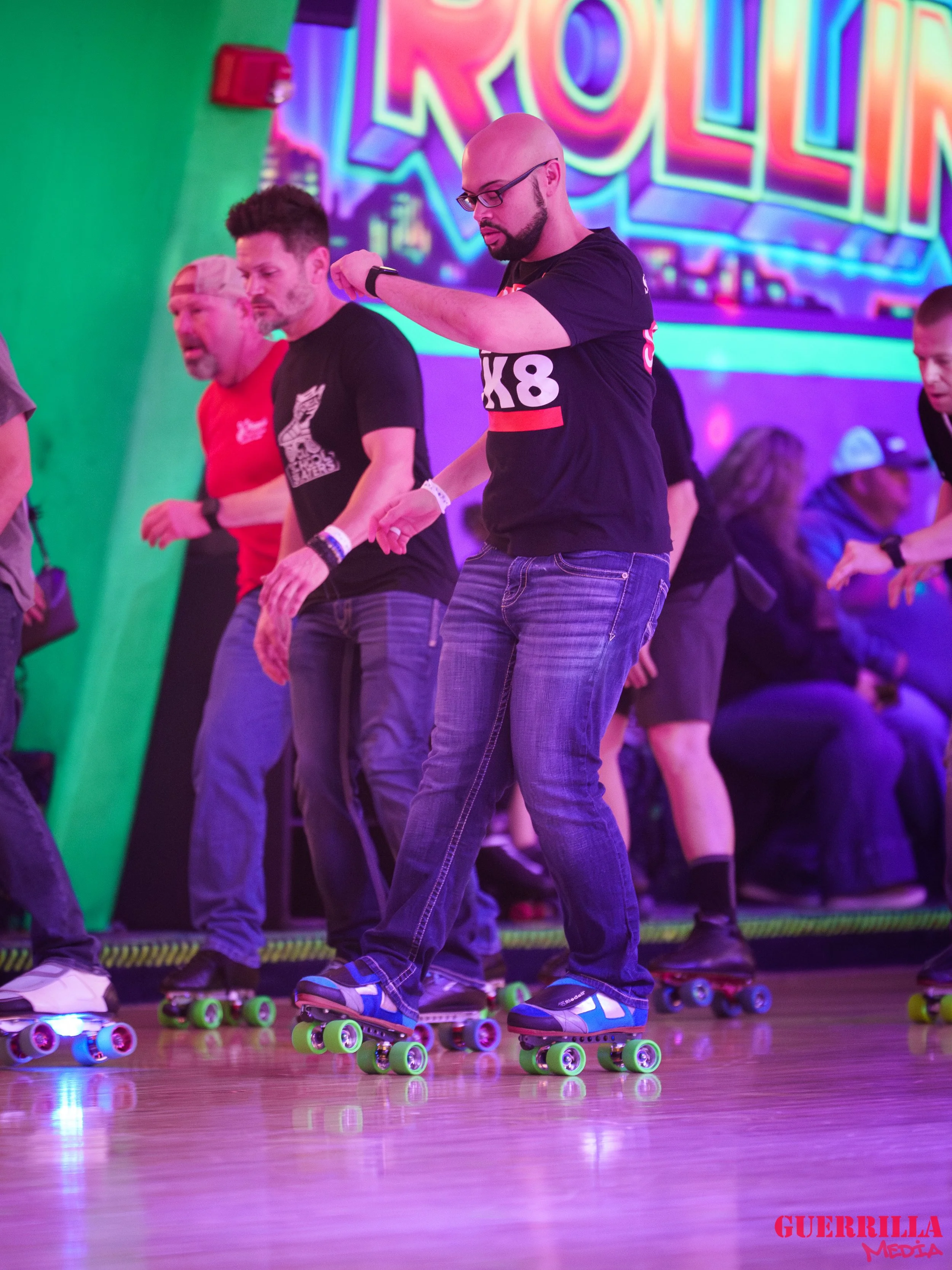 People roller skating indoors at a roller disco with colorful neon lights and a vibrant "Roller" sign in the background.