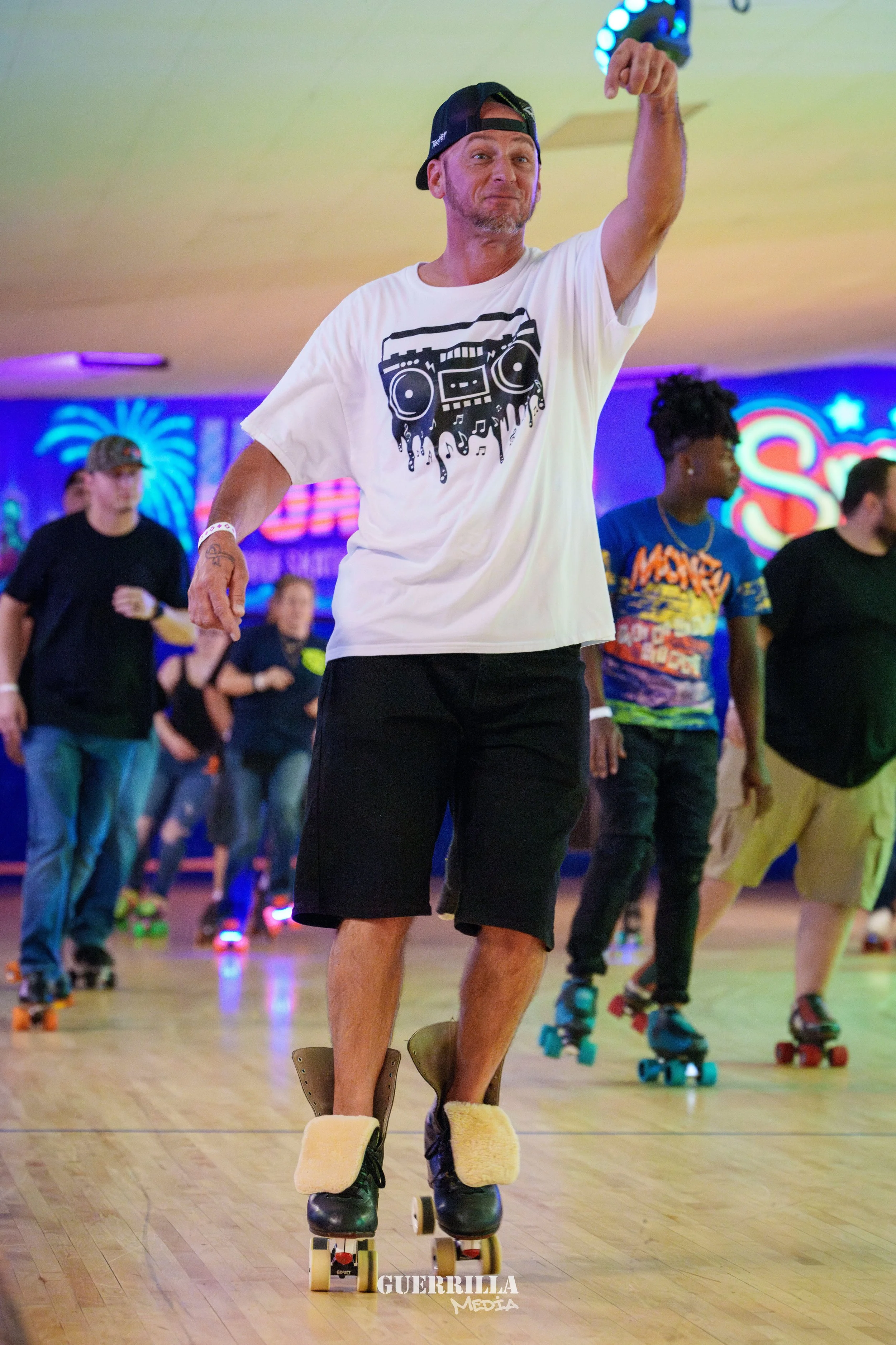 A man roller skating in a roller rink with colorful neon lights and people in the background.