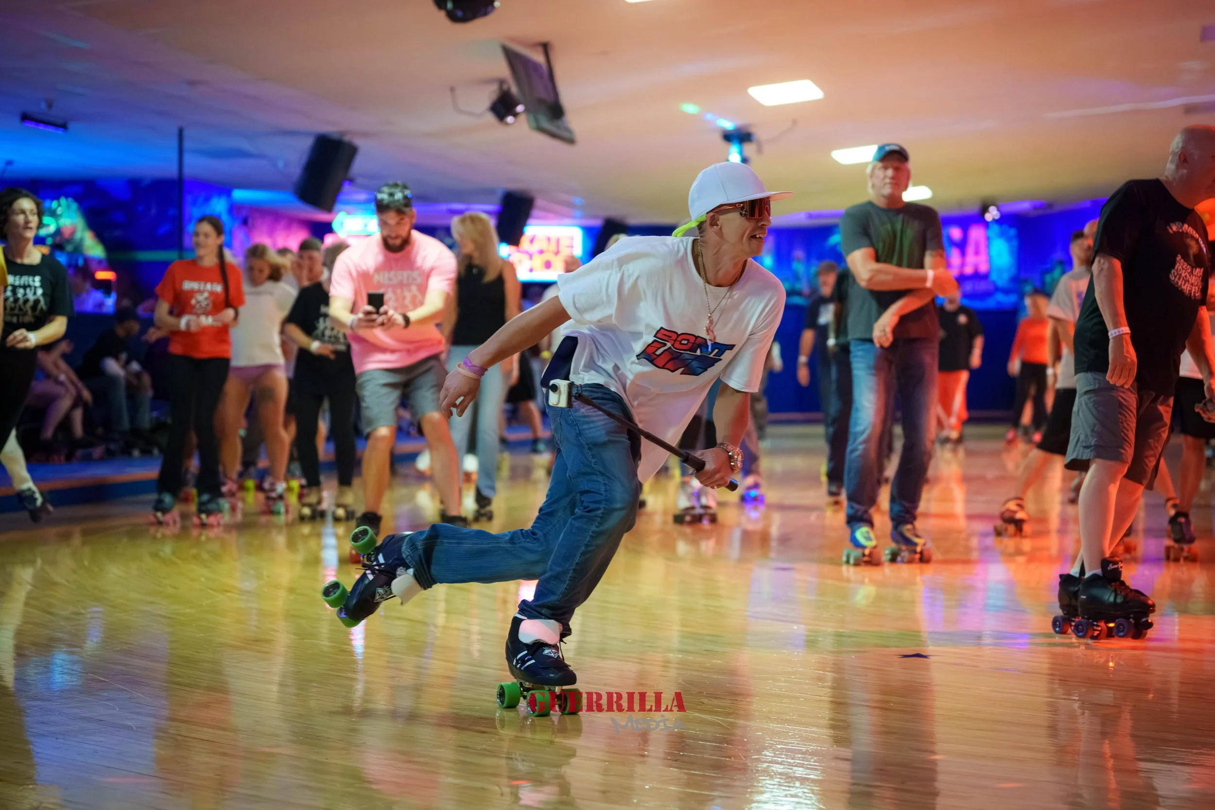 People roller skating at an indoor roller rink, with colorful lighting and a wooden floor.