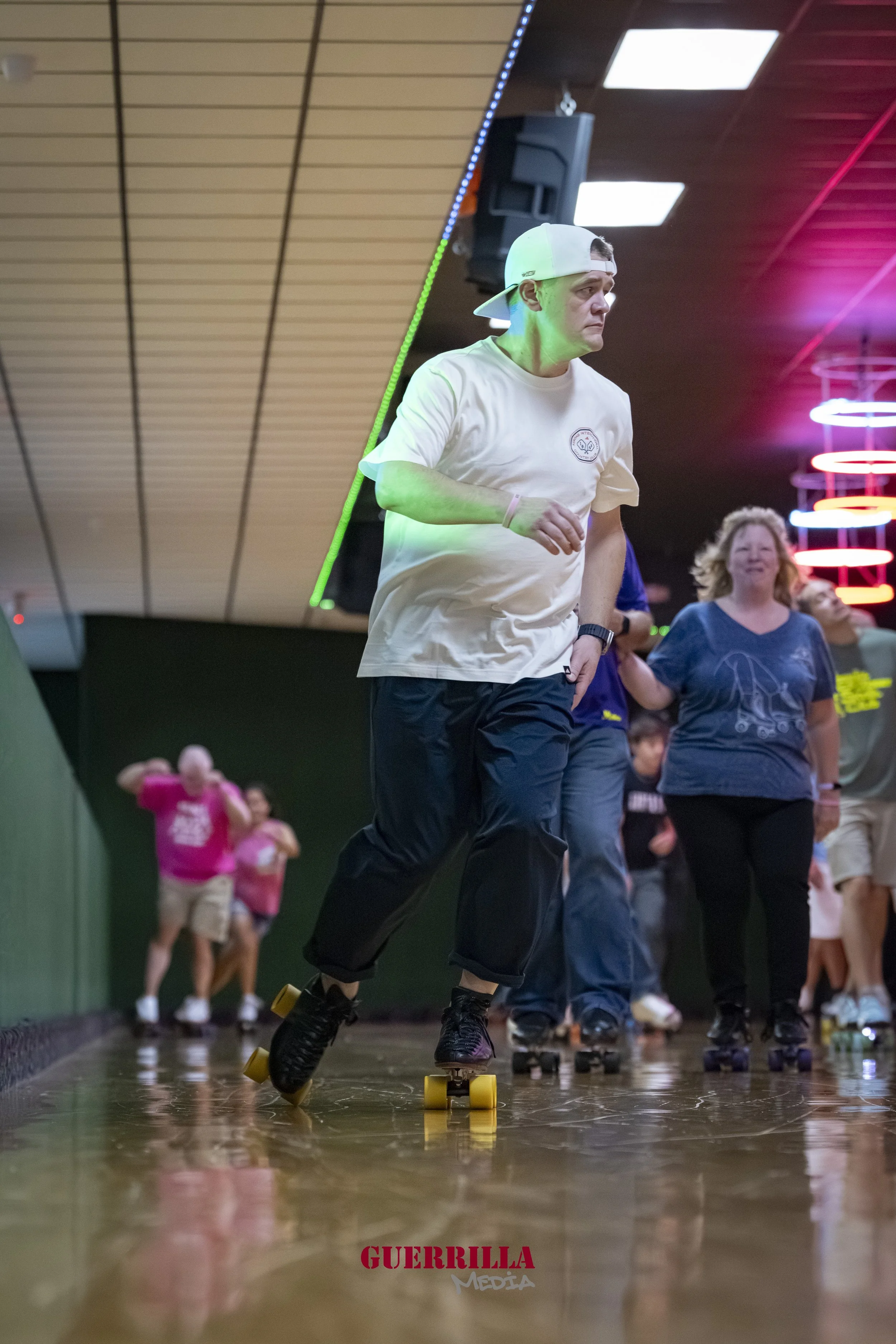 People roller skating indoors, with colorful neon lights and wooden floors.
