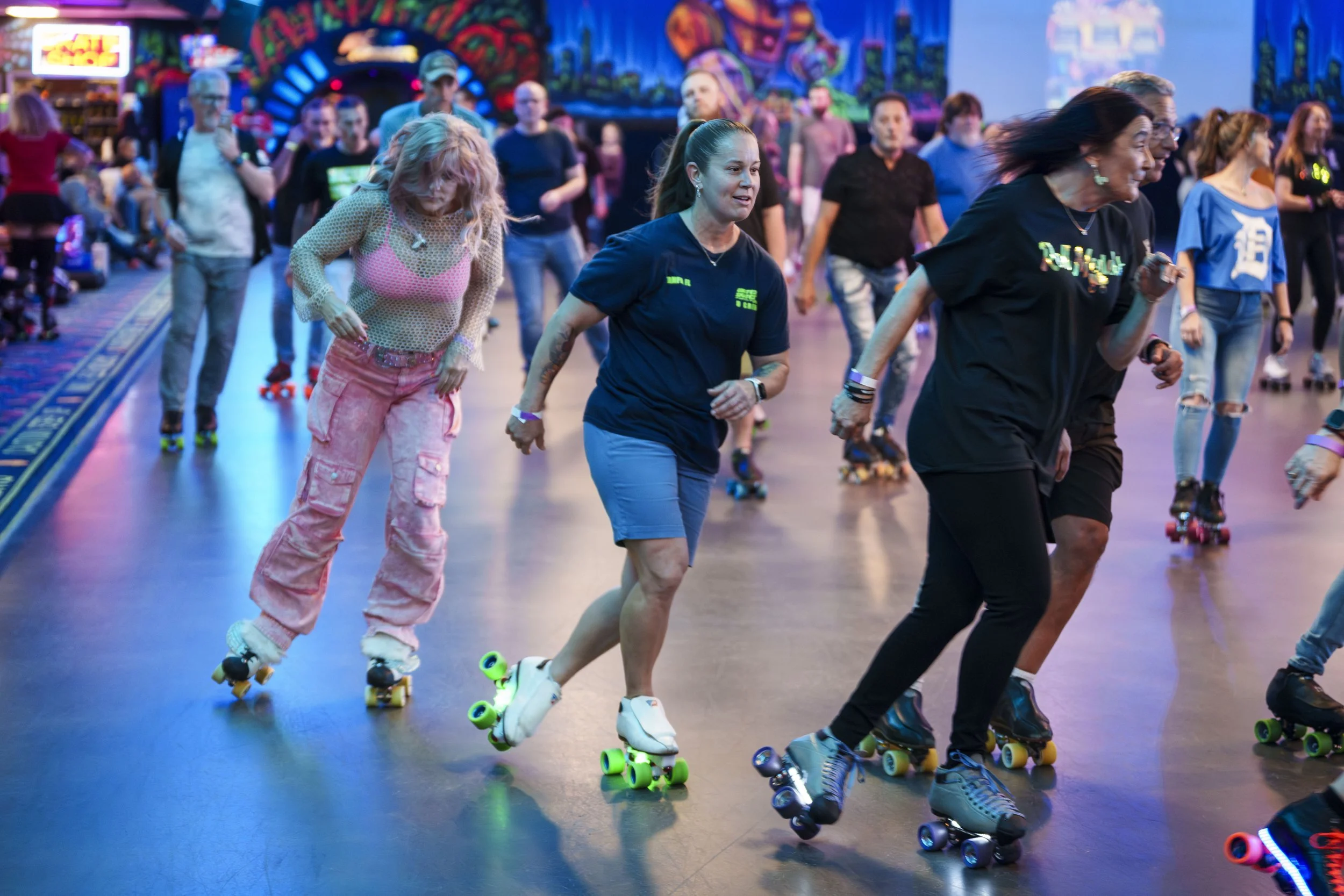 People roller skating indoors with colorful lights and vibrant background.