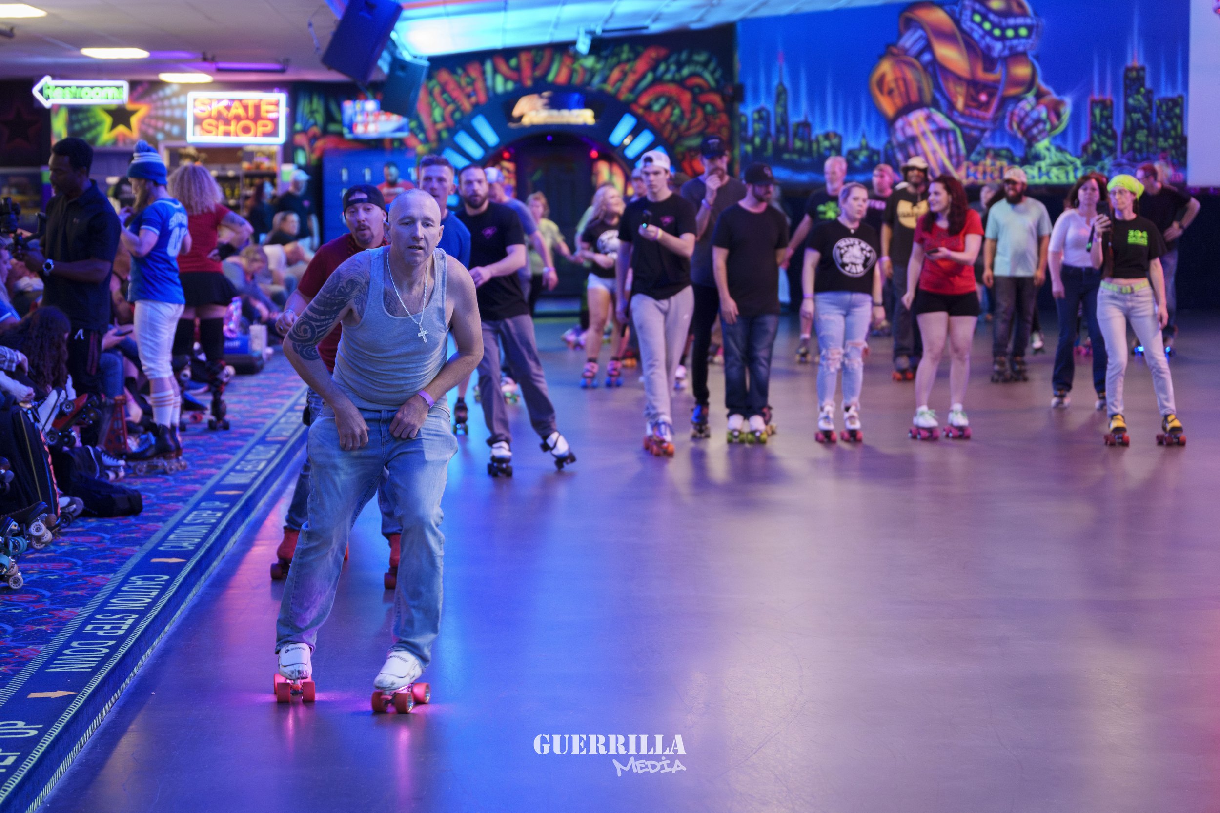 People roller skating in an indoor roller rink with vibrant neon lighting and cityscape murals on the walls.
