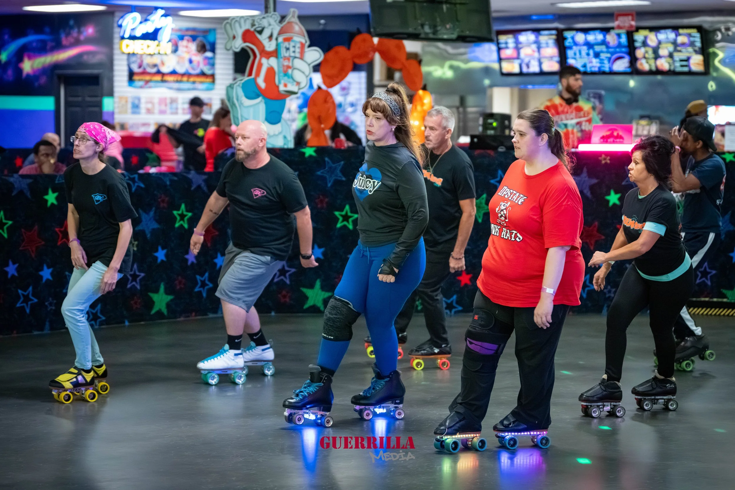 Group of people roller skating at an indoor roller rink decorated with colorful stars and vibrant lights.