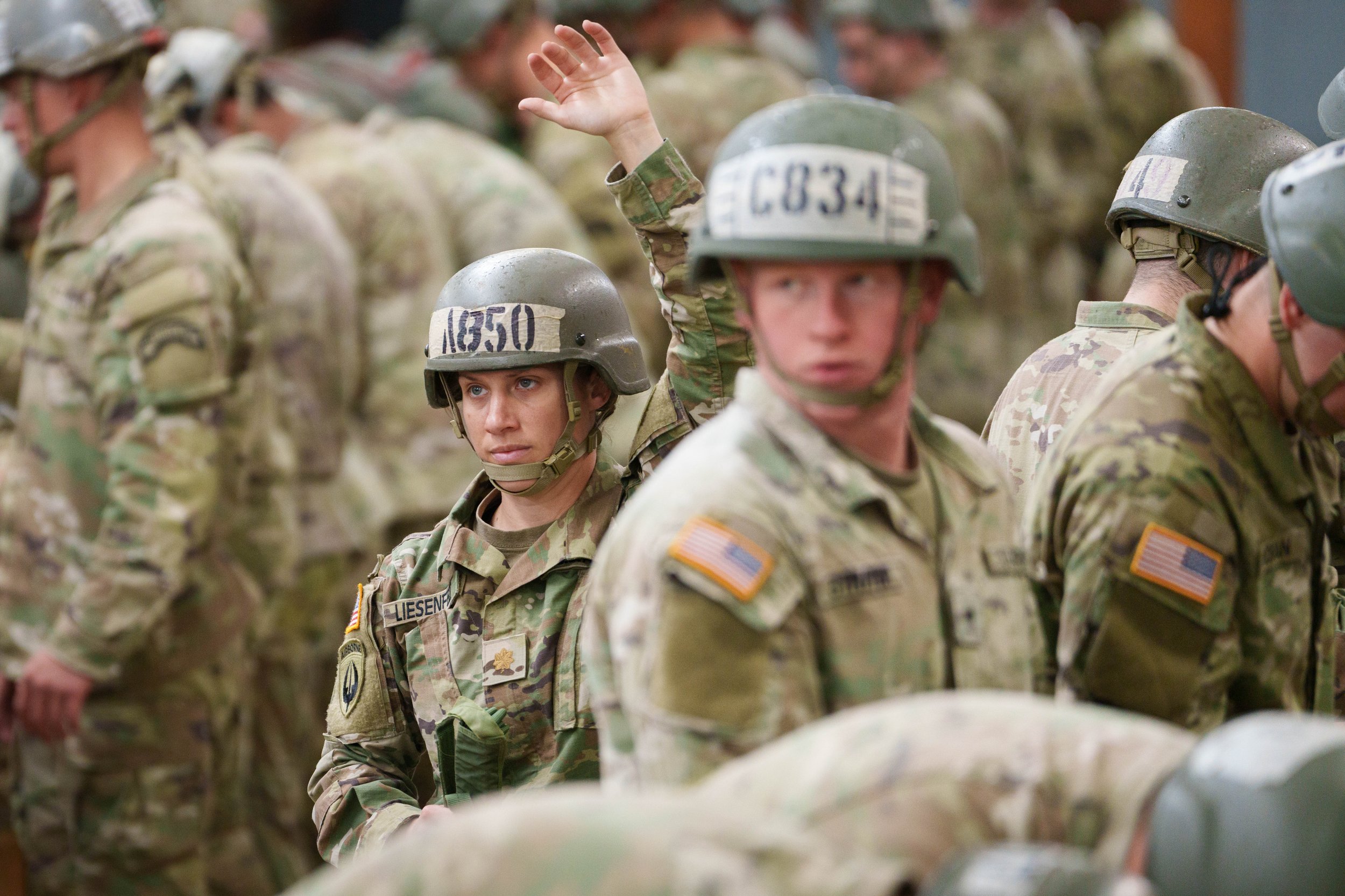 A group of soldiers wearing camouflage uniforms and helmets, standing in formation during a military event or training.
