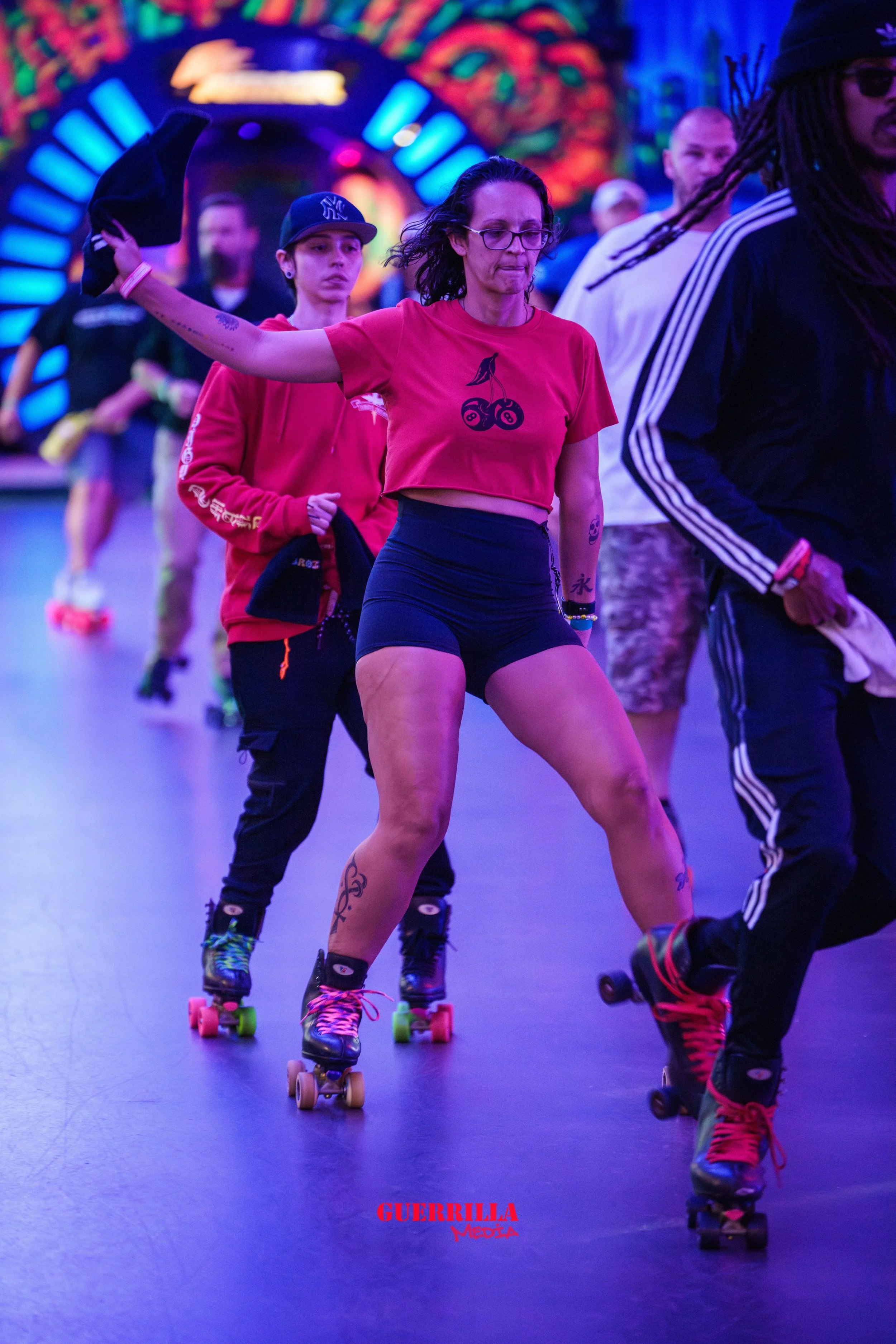 People roller skating in an indoor skate rink with colorful neon lights and a vibrant background.