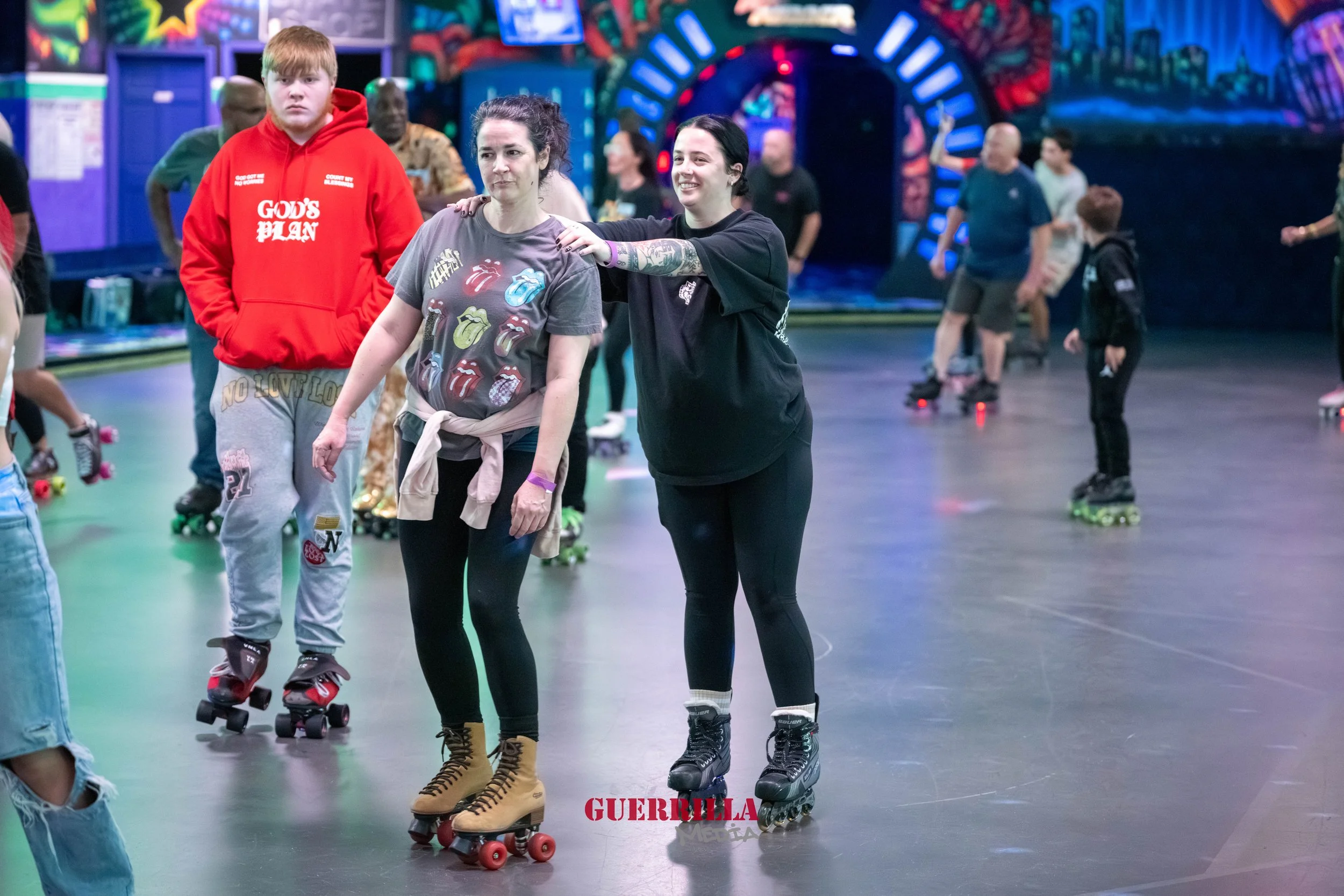 People roller skating in an indoor skating rink with colorful neon lights and cityscape murals on the walls.