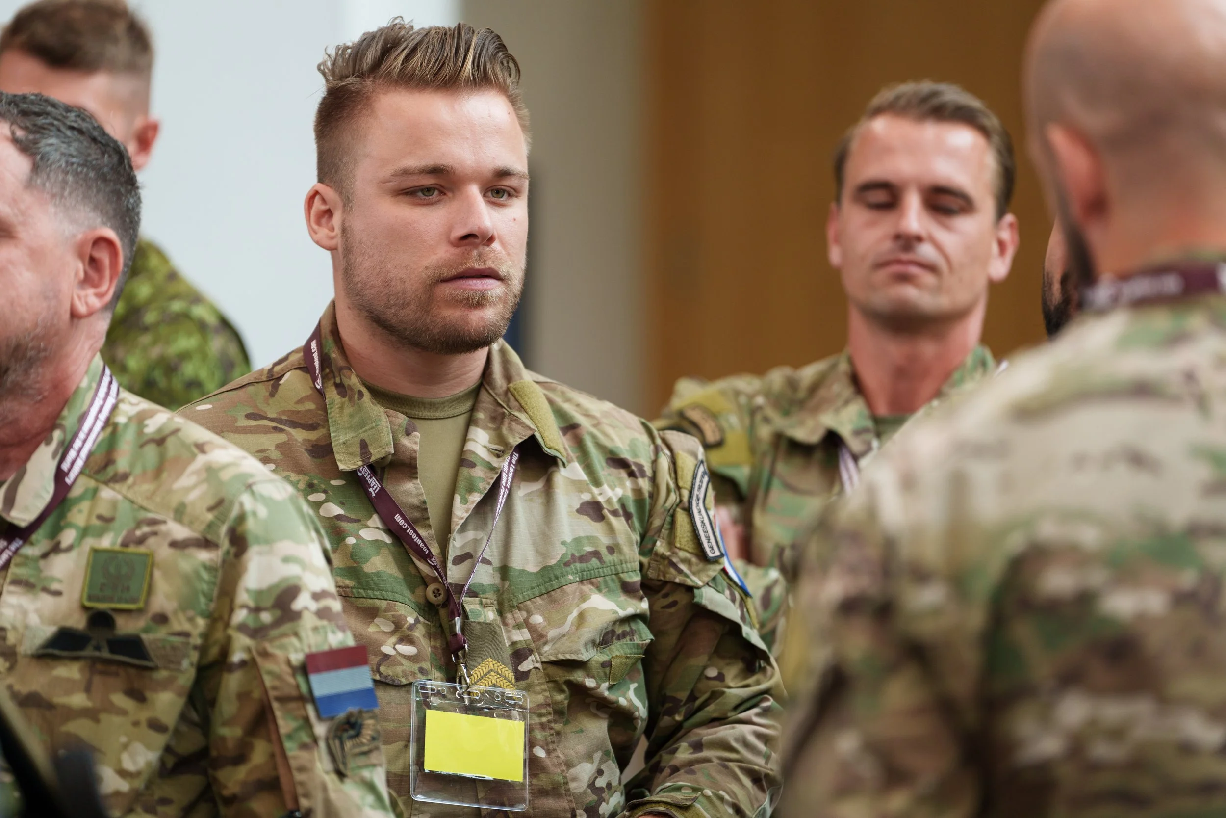 Military personnel in camouflage uniforms during a serious meeting or briefing.