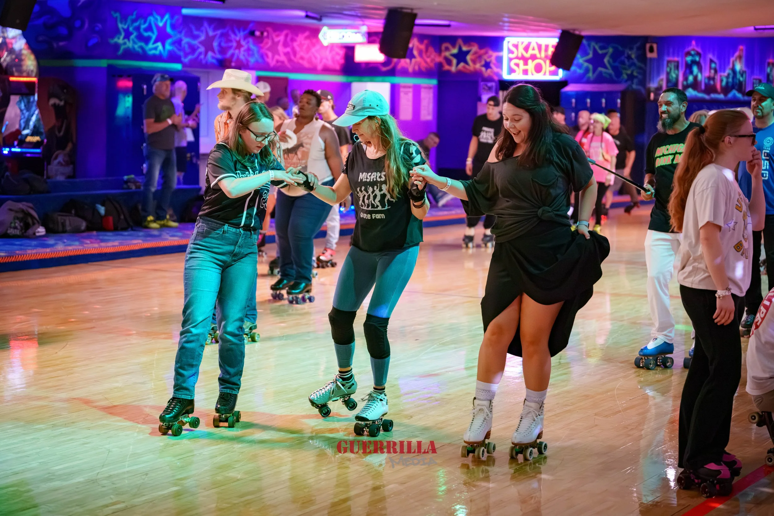 People roller skating at a roller rink with colorful neon lighting and signs, including a skate shop sign in the background.